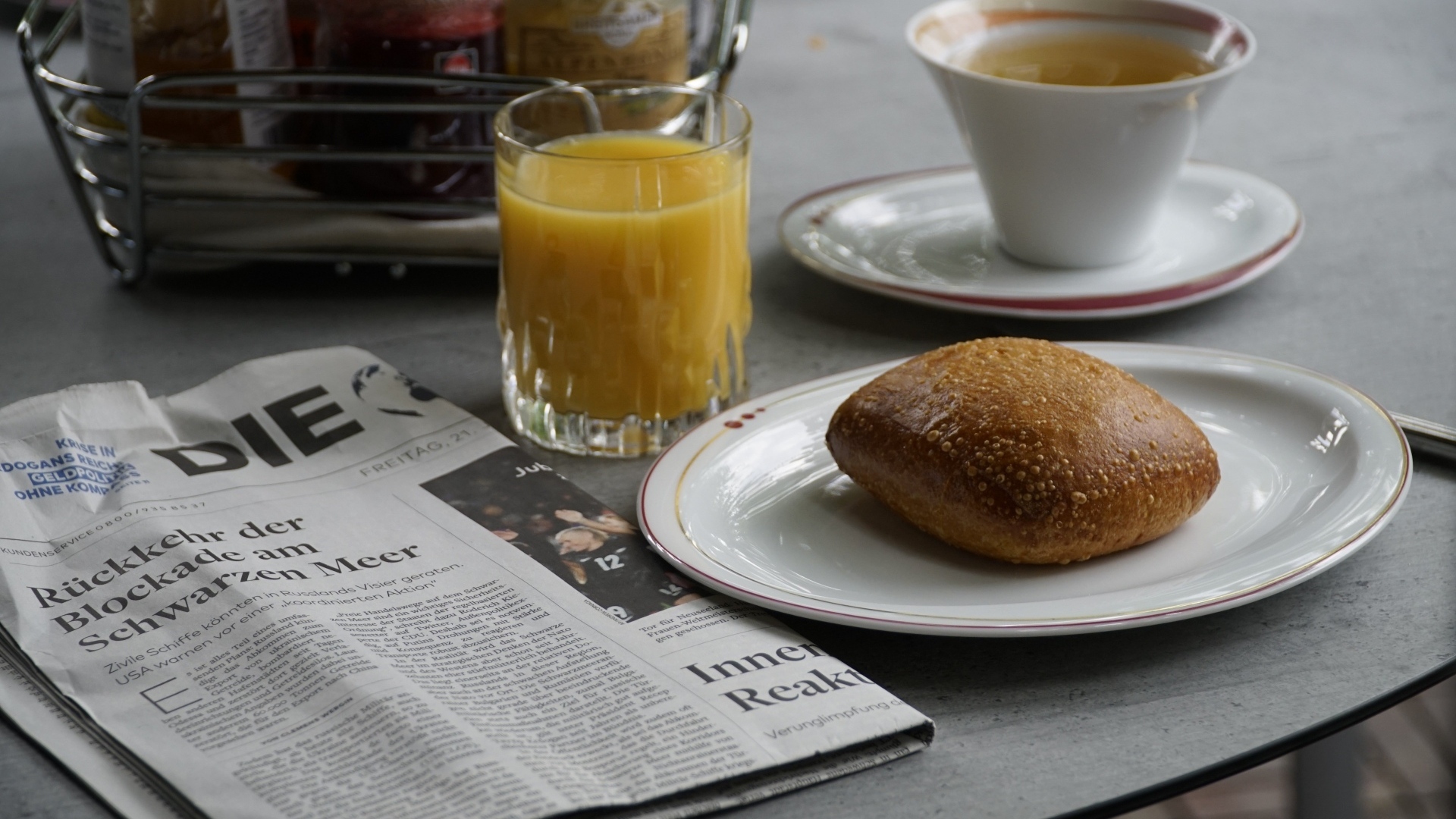 Булочка и стакан сока на столе с газетой