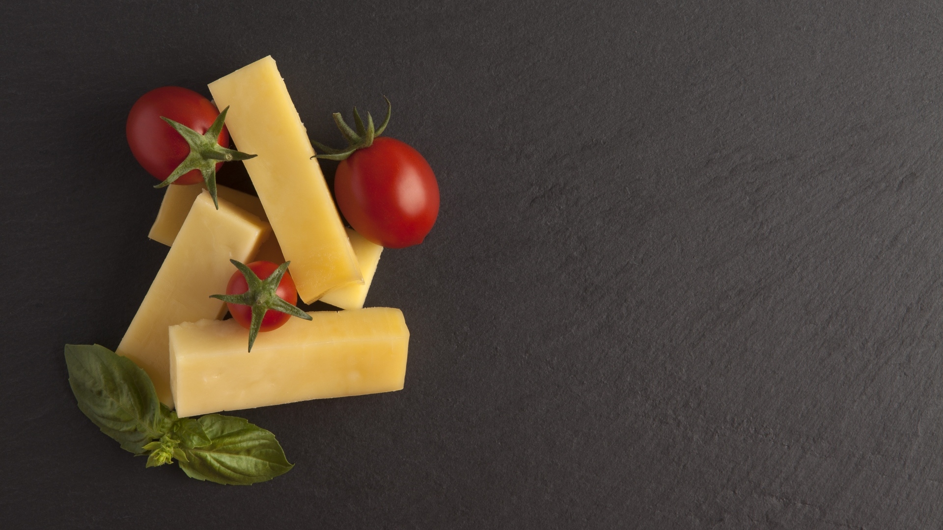 Сыр с помидорами и листьями базилика на сером столе
