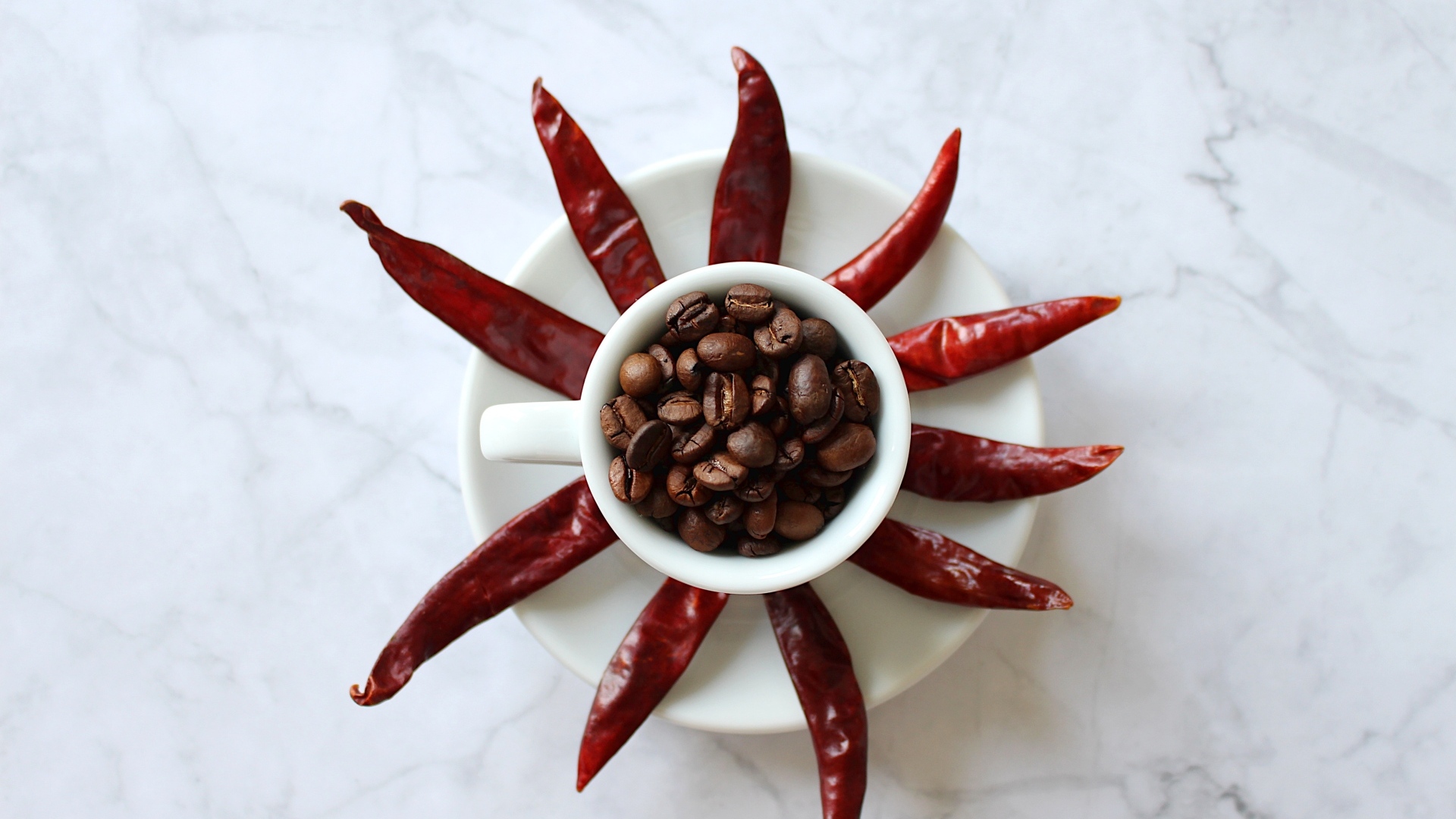 Кофейные зерна в чашке на тарелке с красным перцем