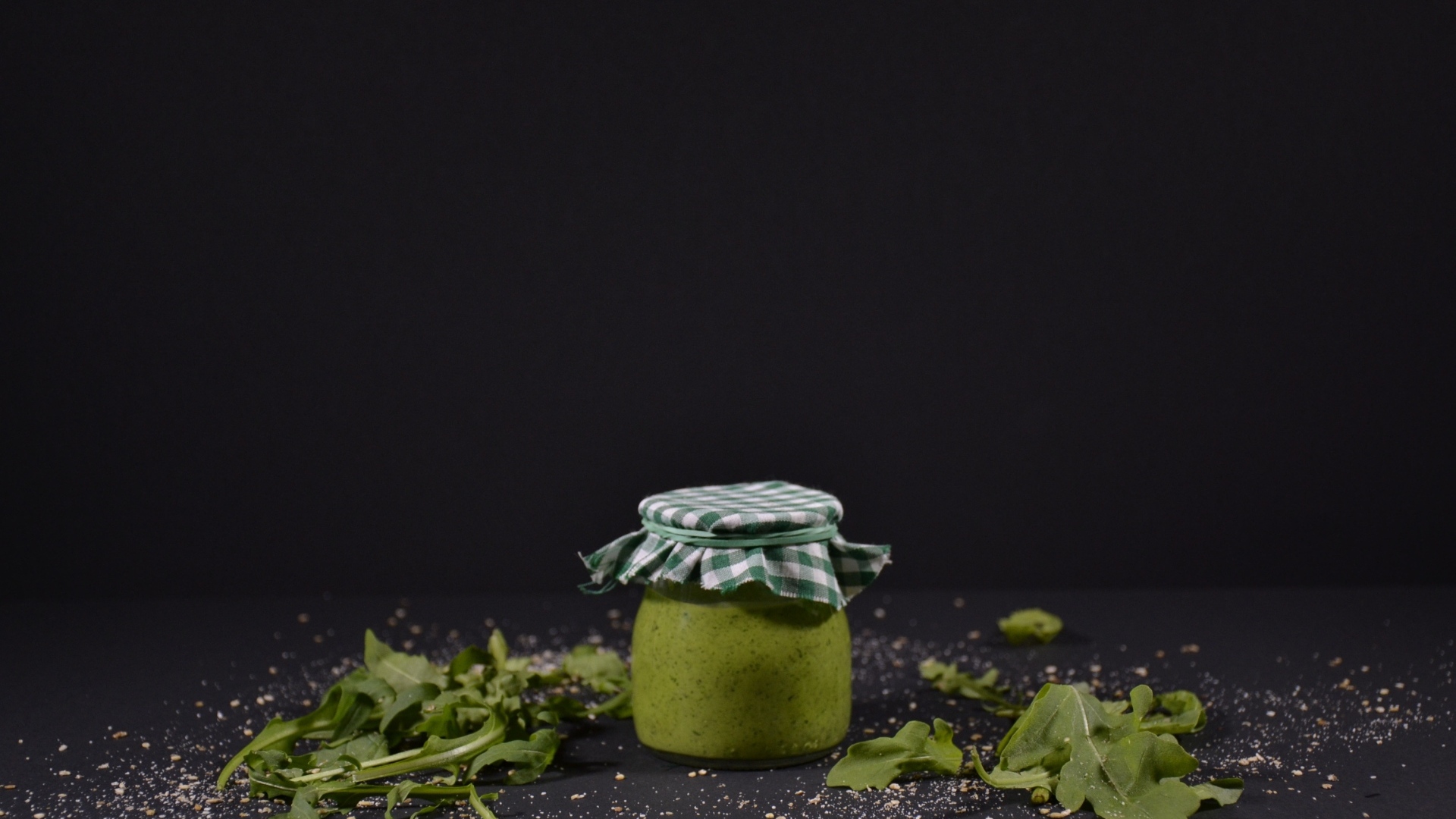 Банка соуса песто на черном фоне