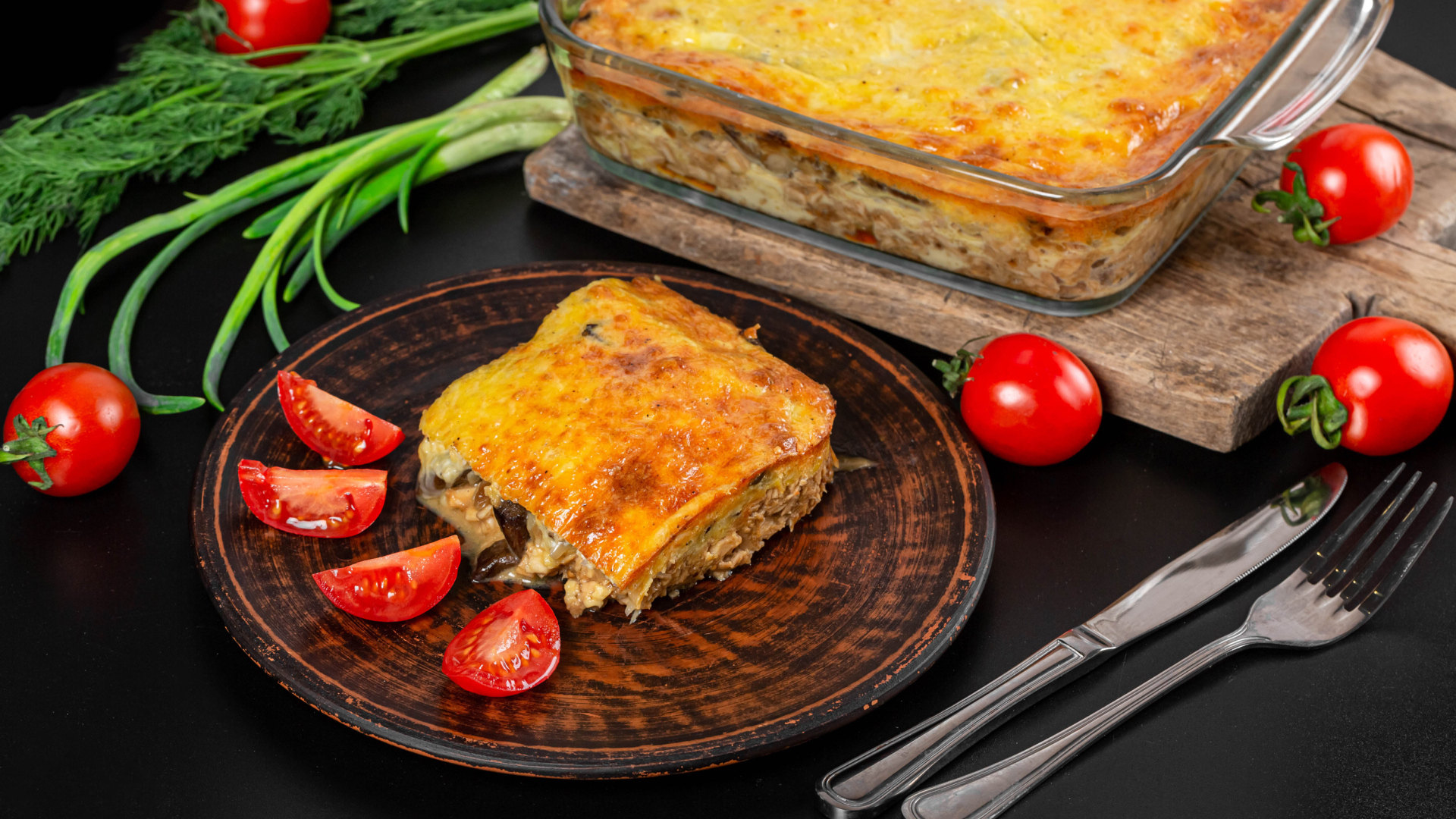 Лазанья на тарелке с помидорами и зеленью