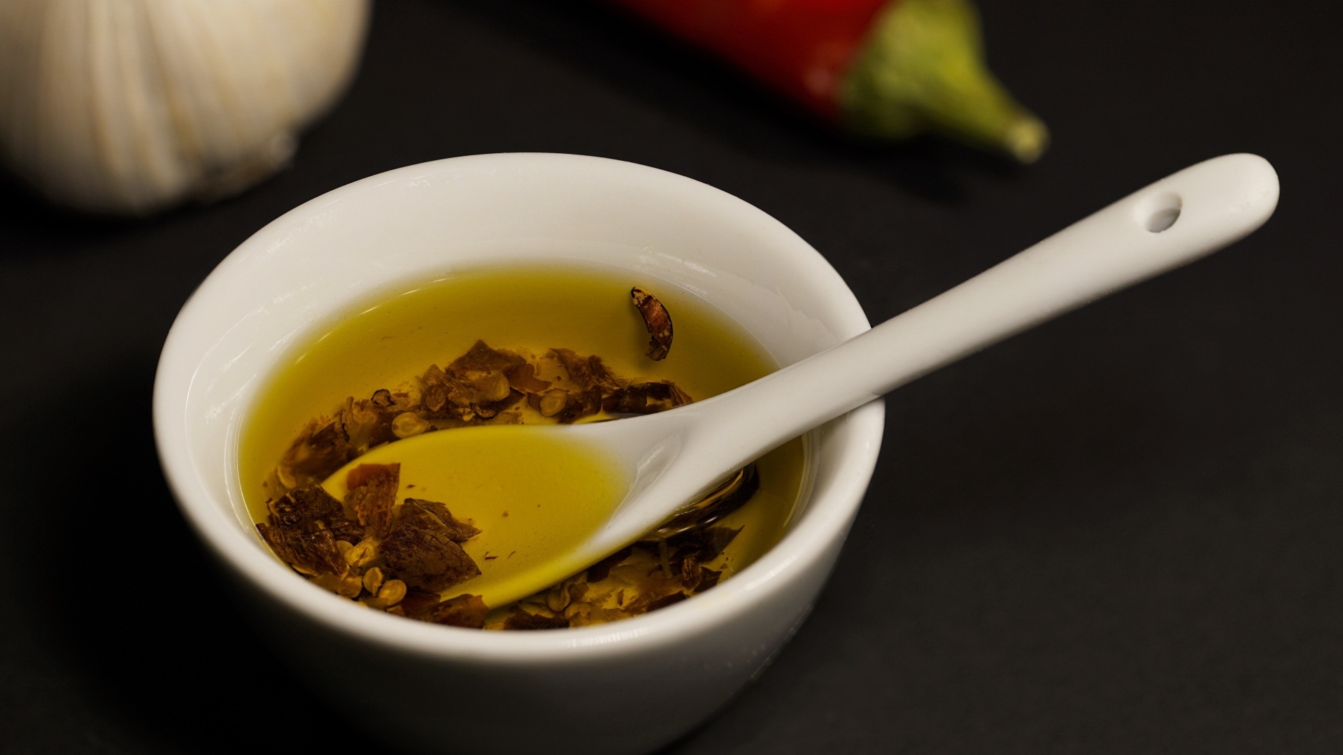 Оливковое масло в тарелке на столе с перцем и чесноком