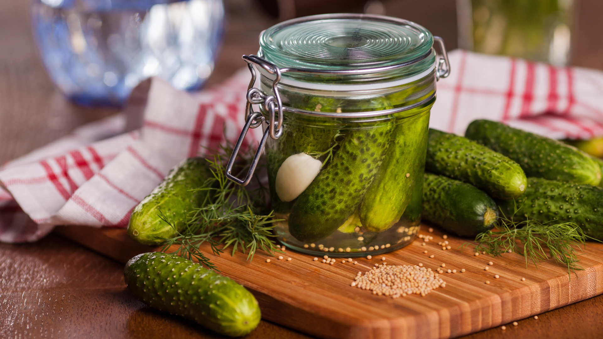 Маринованные огурцы в банке на столе со свежими