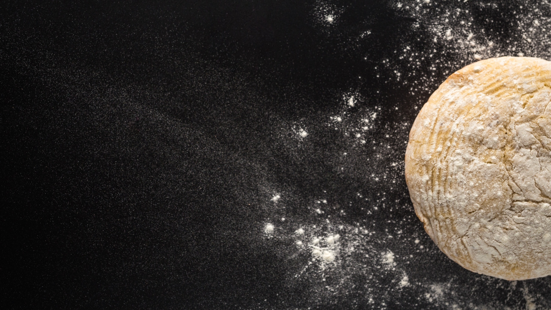 Сырое тесто на черном столе с мукой