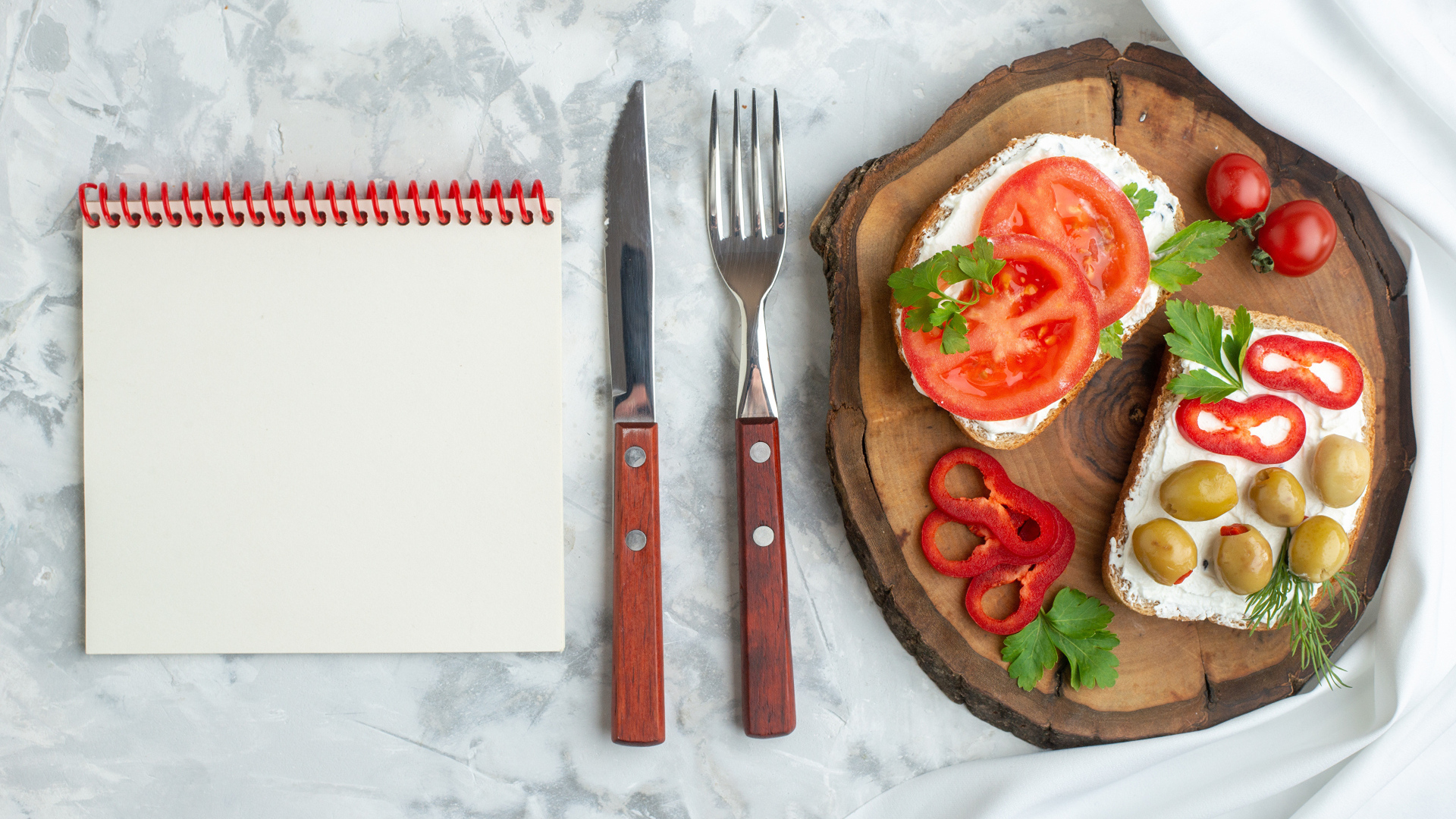 Бутерброды на столе со столовыми приборами и блокнотом