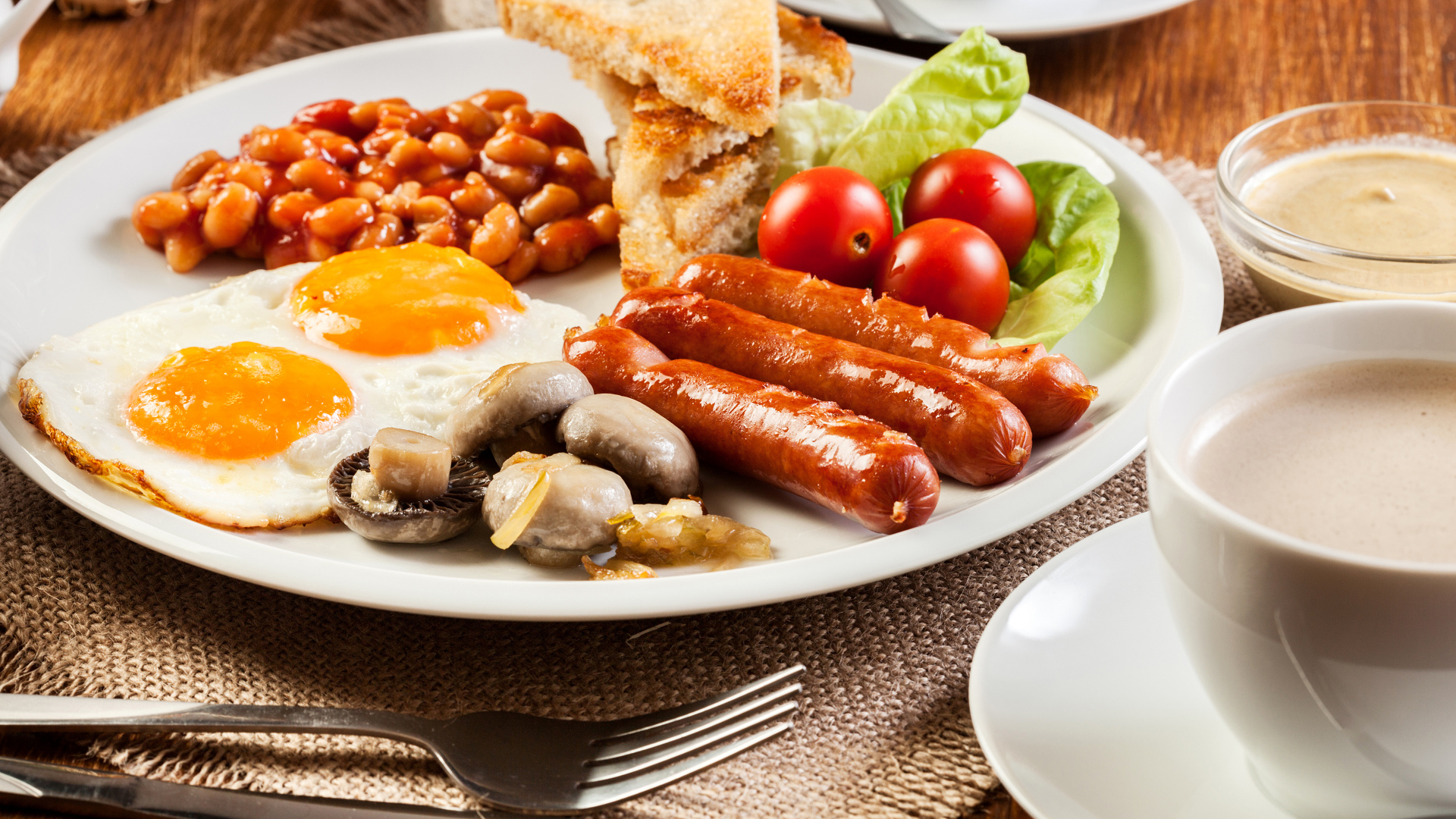 Яичница, сосиски и овощи на тарелке на завтрак