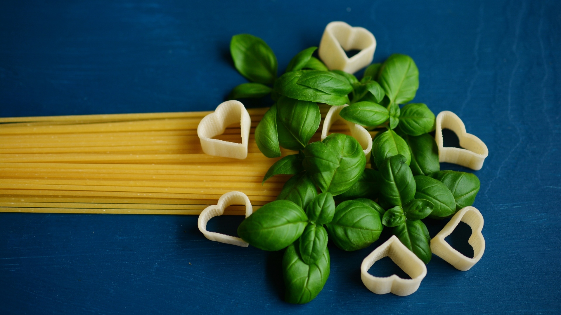 Спагетти на синем фоне с листьями базилика