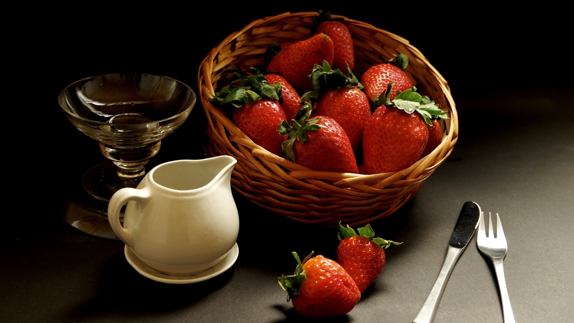 Корзина со спелой красной клубникой на столе с посудой