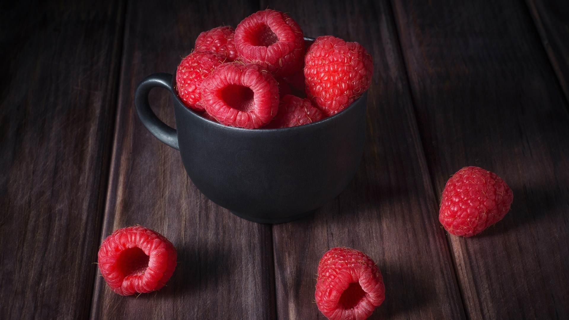 Черная чашка с красными ягодами малины