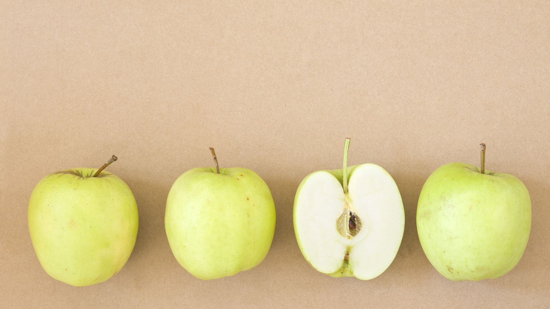 Четыре зеленых яблока на бежевом фоне 