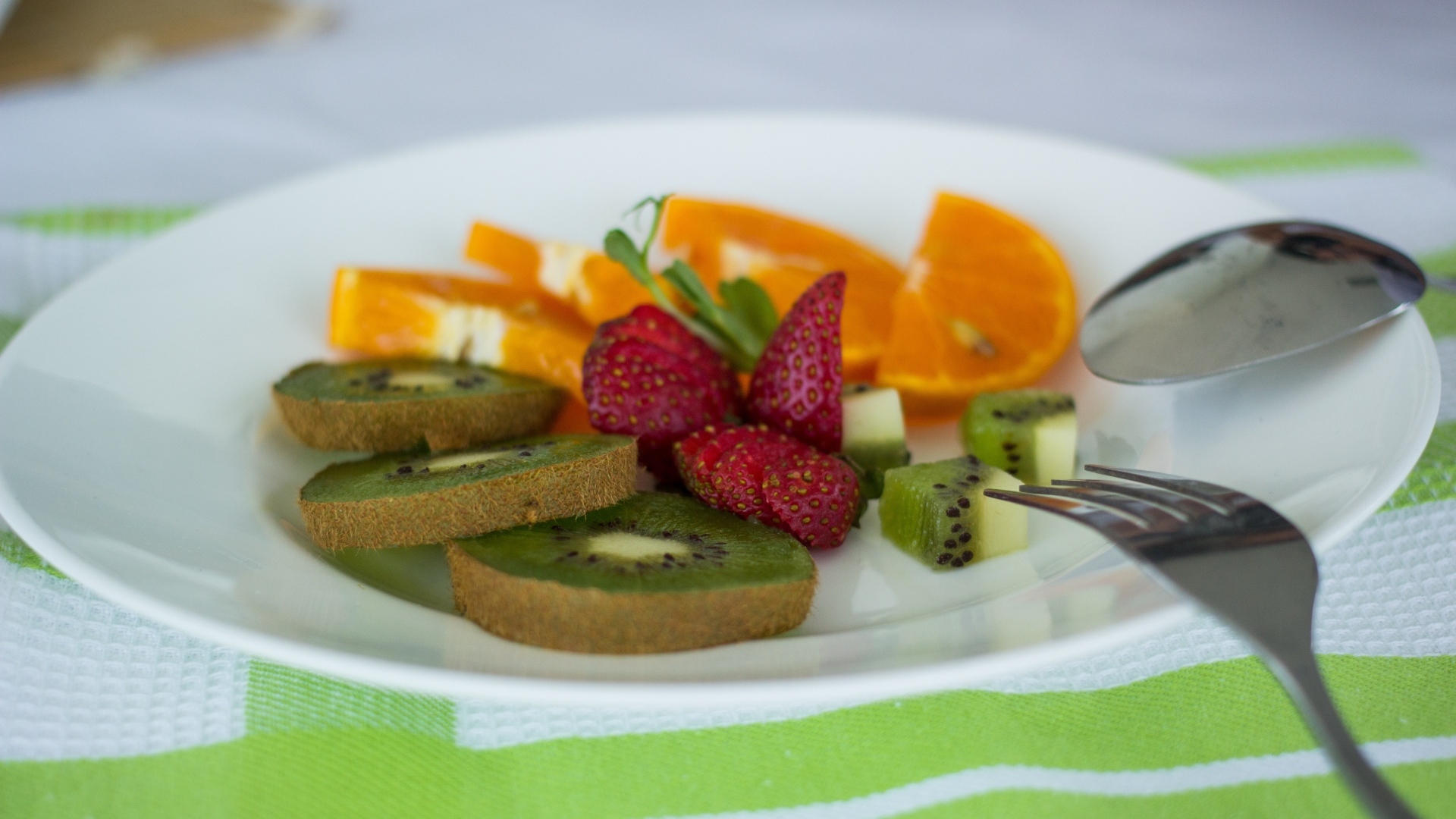 Свежие нарезанные фрукты на тарелке с вилкой