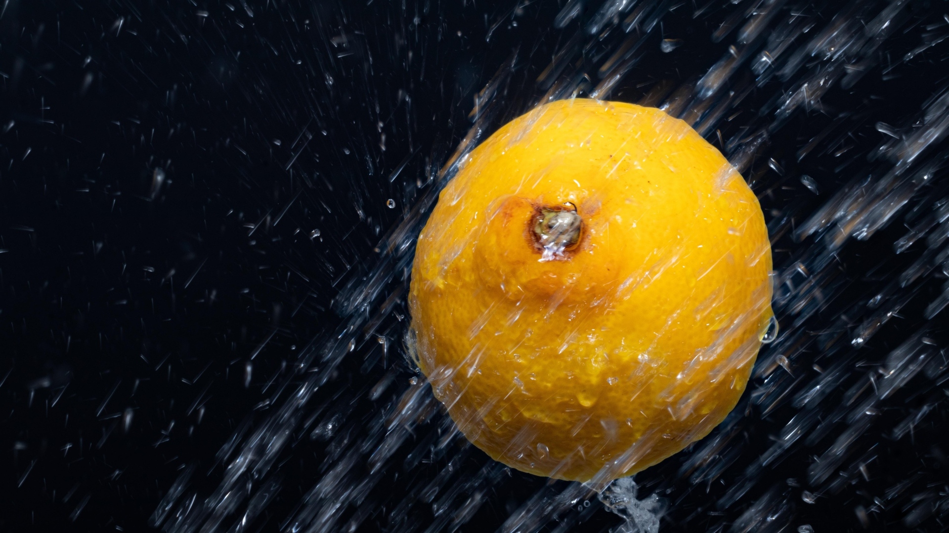 Лимон в брызгах воды на черном фоне