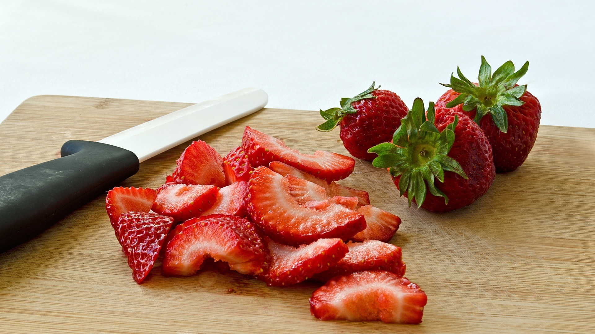 Красная клубника нарезана на деревянной доске