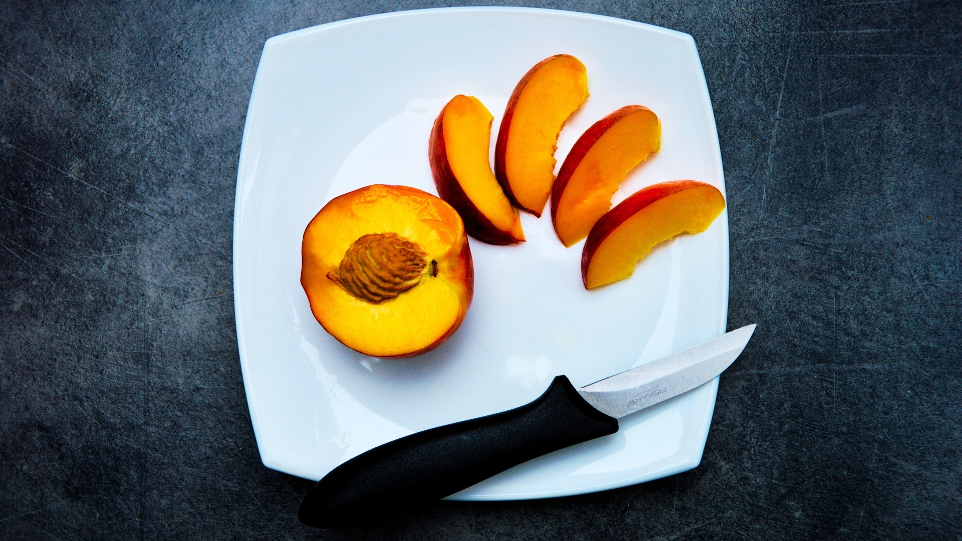 Нарезанный персик на белой тарелке