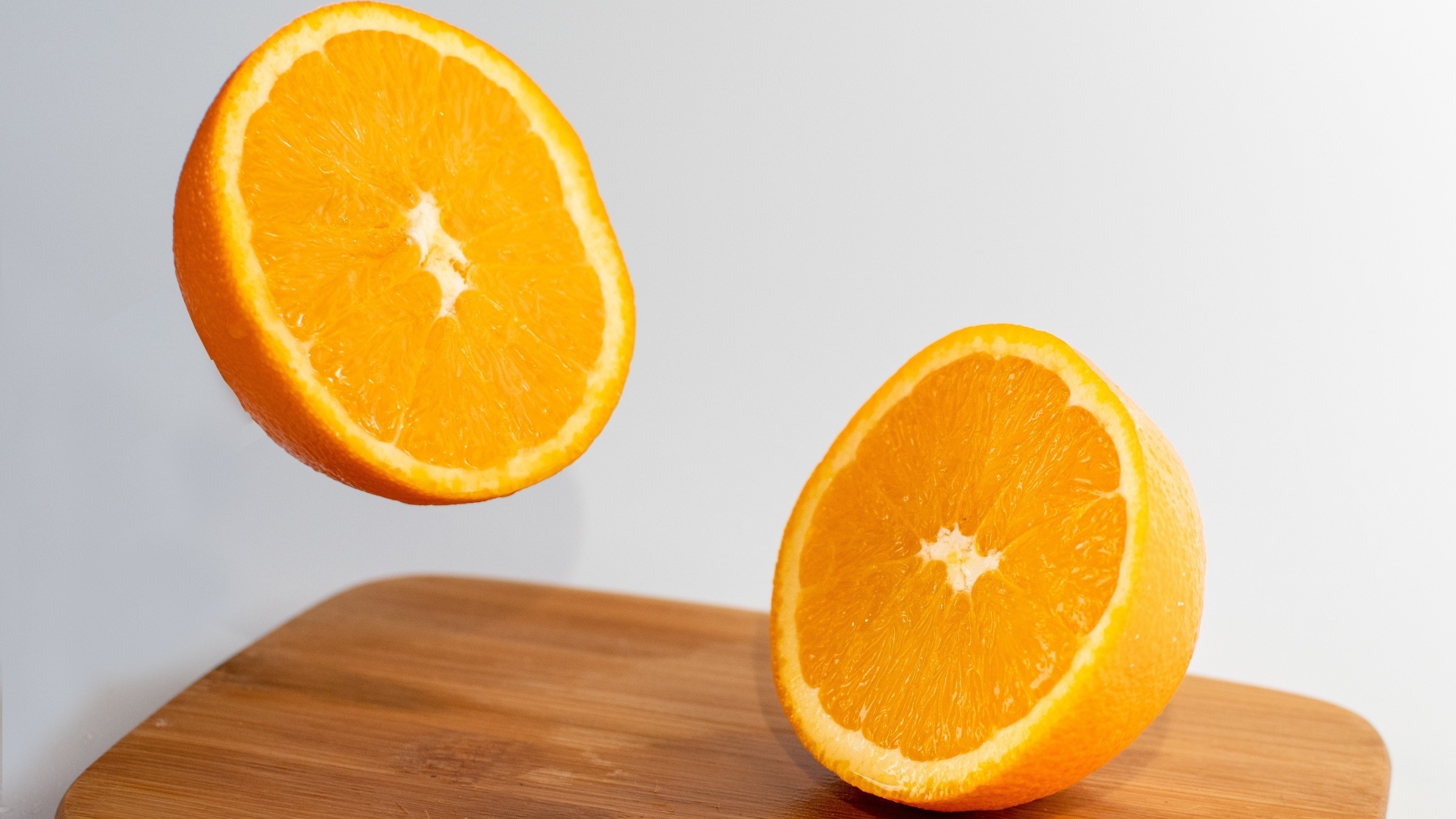 Две половинки апельсина на деревянной доске
