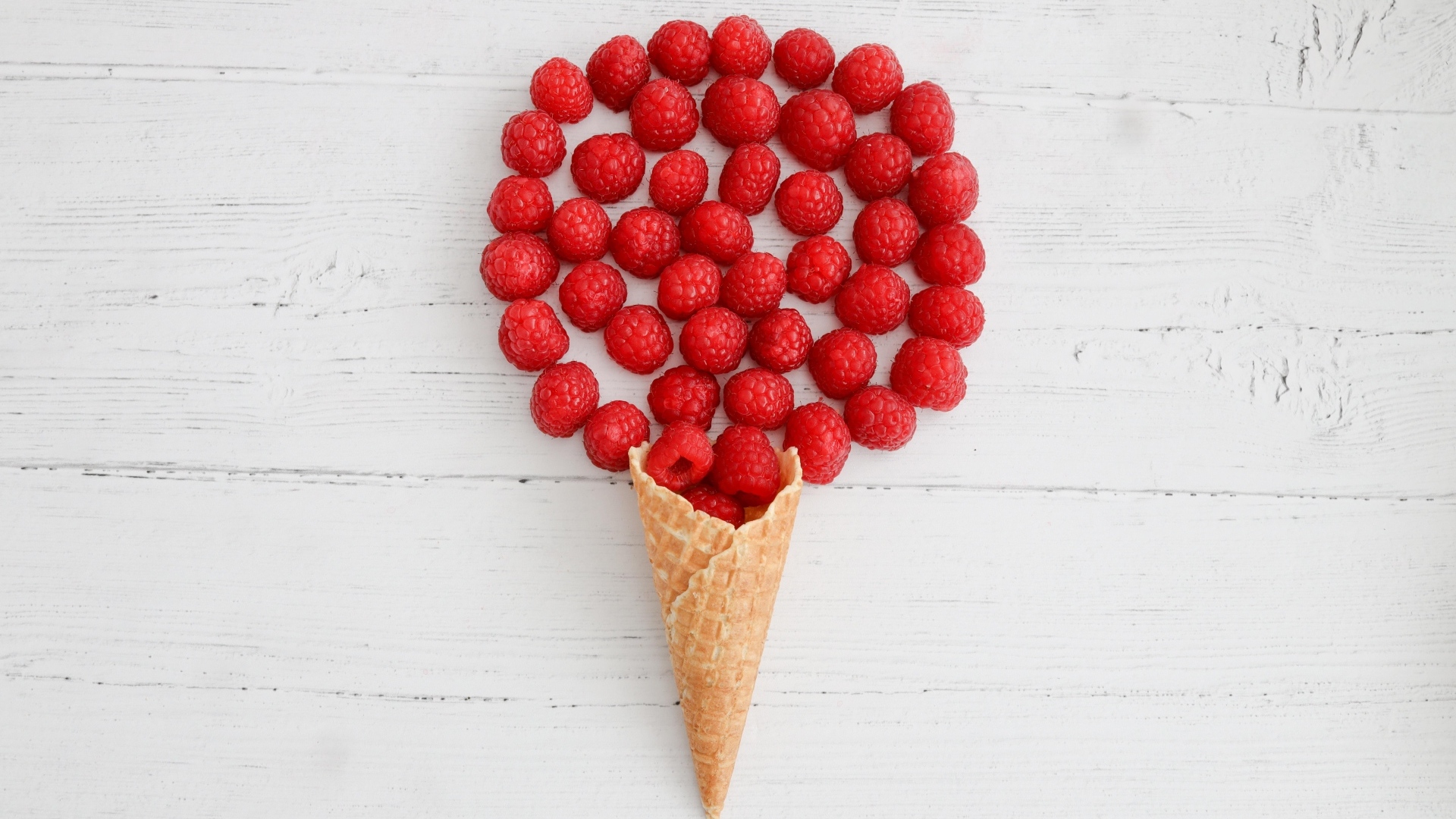 Вафельный рожок с ягодами малины на белом столе