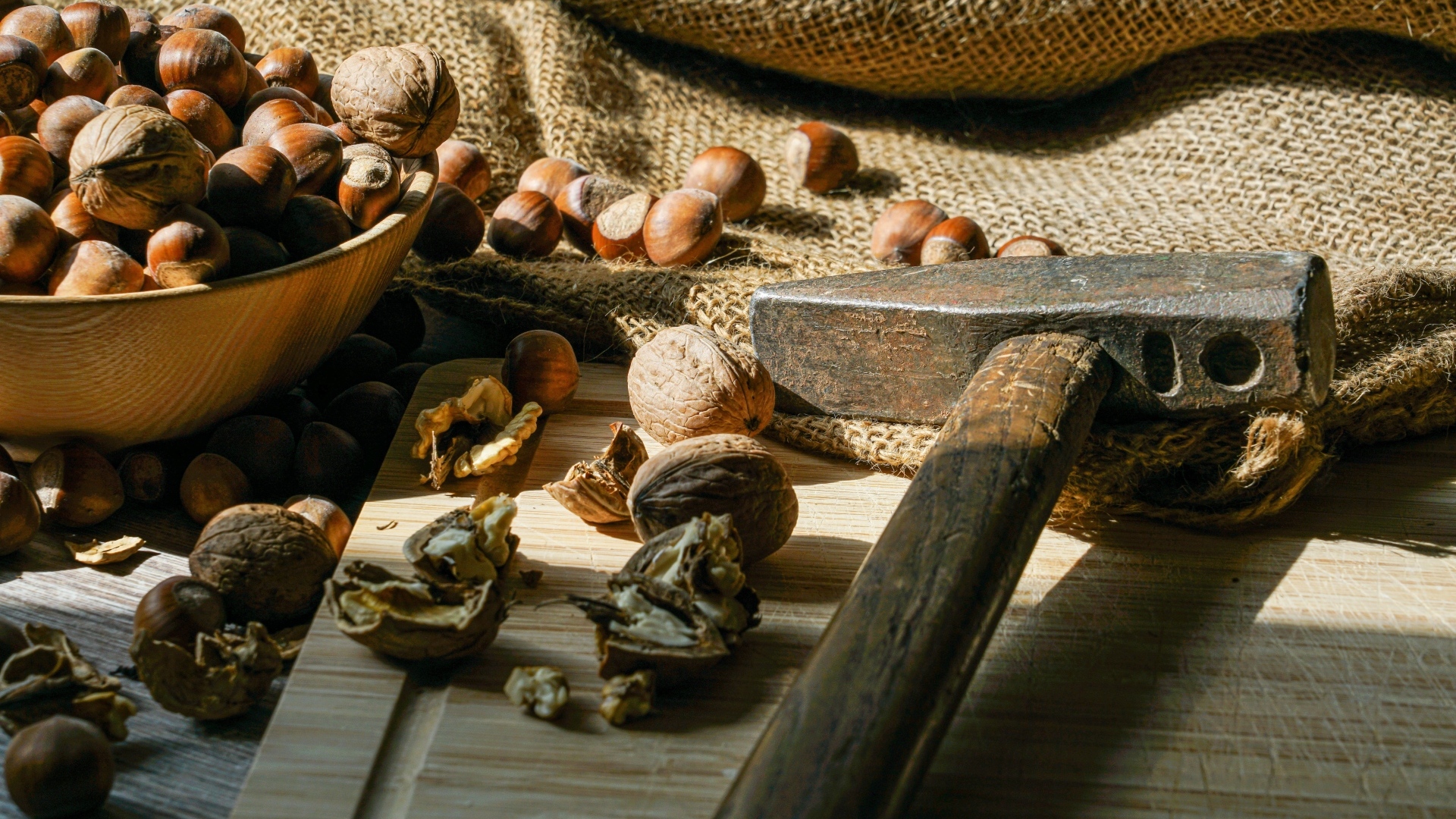 Грецкие орехи и фундук на столе с молотком