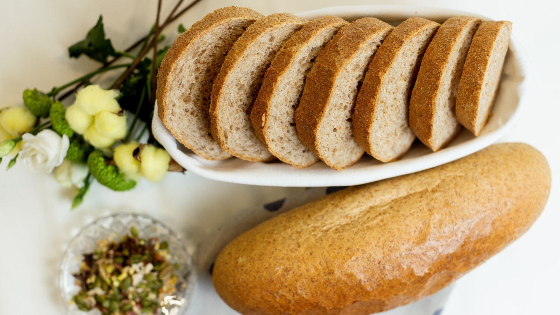 Батон нарезанный на столе с цветами