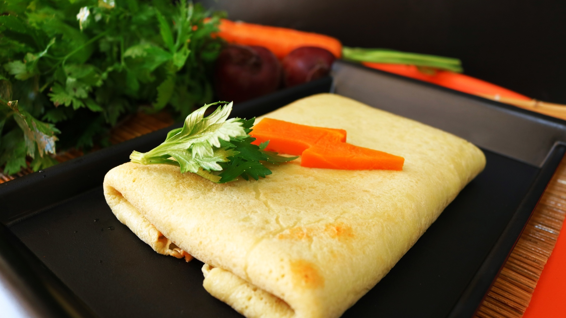 Блинчик на тарелке с морковью и веточками петрушки