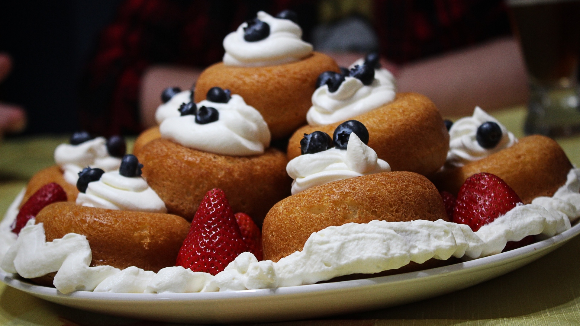 Пирожные на тарелке со взбитыми сливками и ягодами