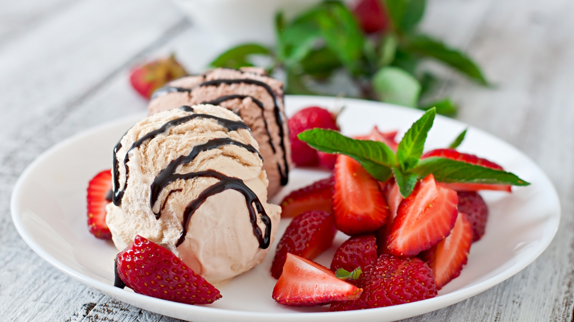 Шарики мороженого на тарелке с кусочками клубники