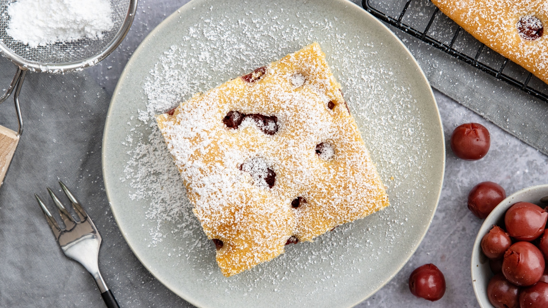 Кусок вишневого пирога на тарелке с сахарной пудрой