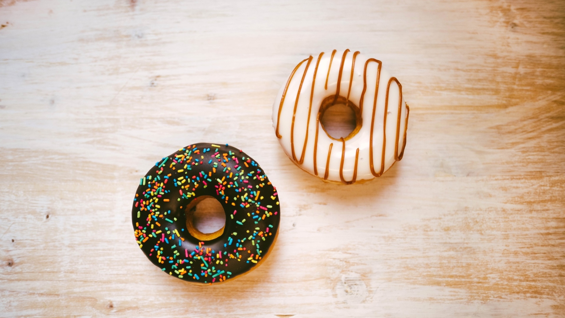 Два пончика в глазури на деревянном столе