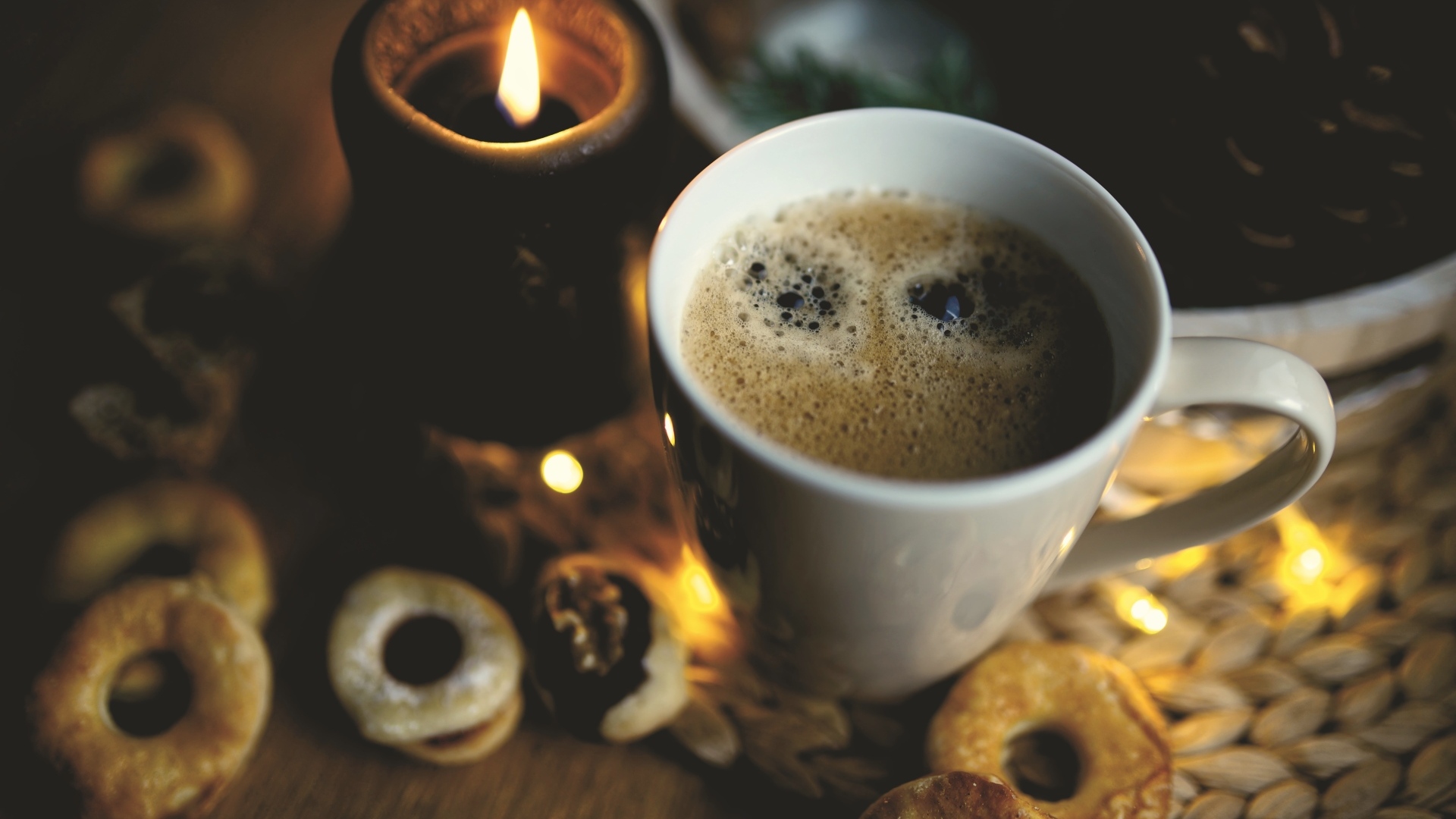 Чашка кофе на столе со свечой и печеньем