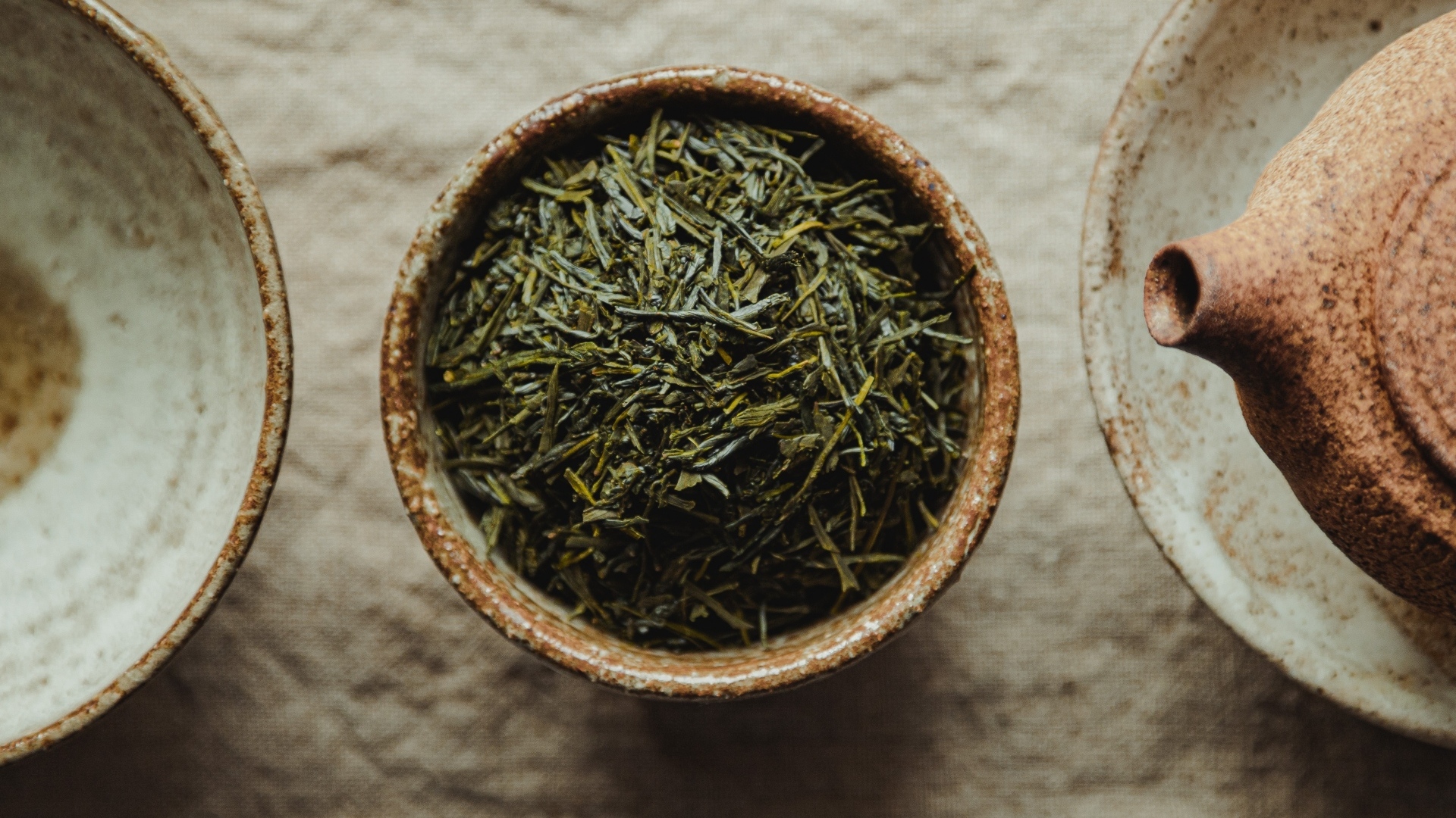 Зеленый чай в пиале на столе с чайником