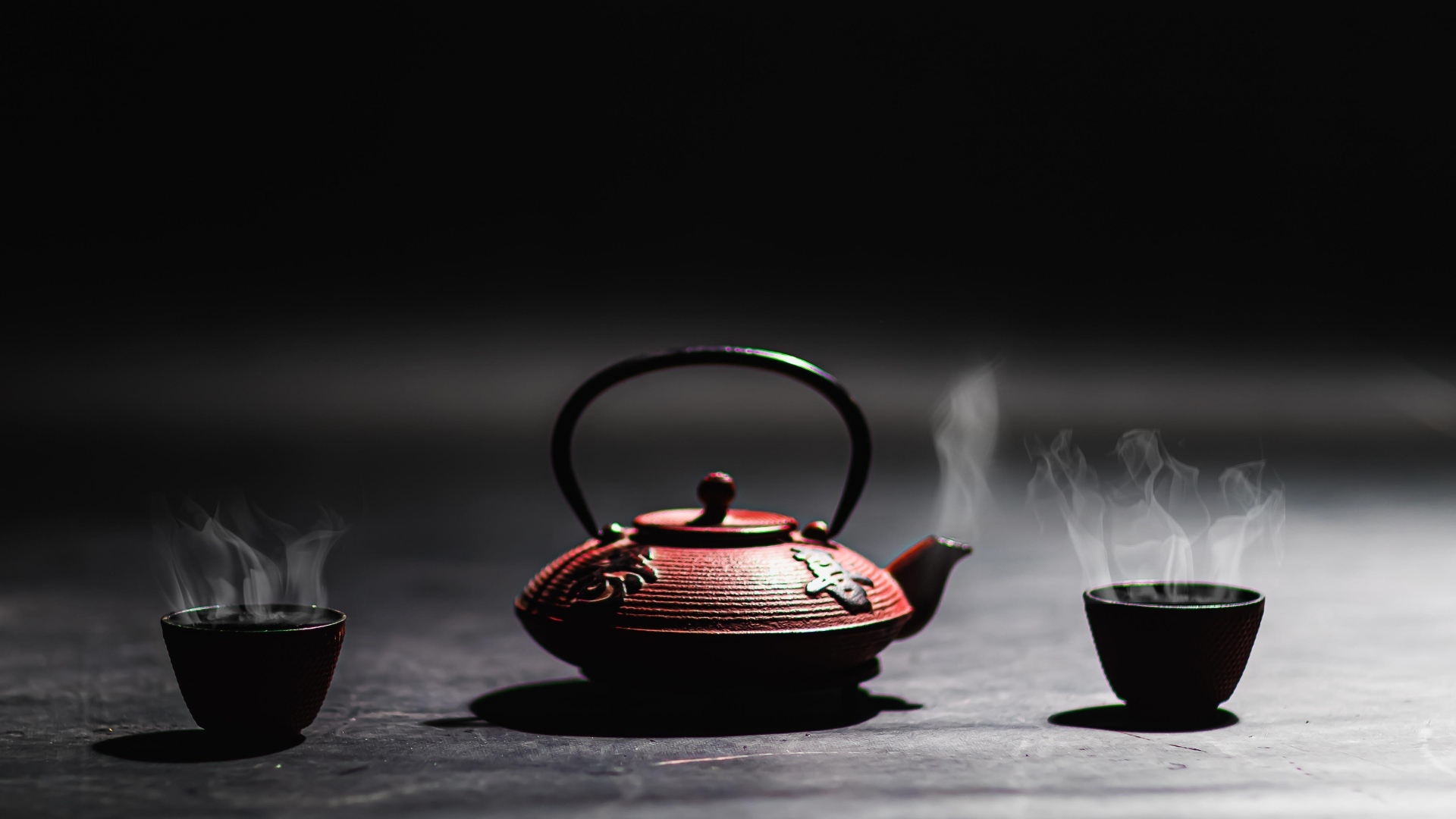 Чайник с горячим чаем на черном фоне