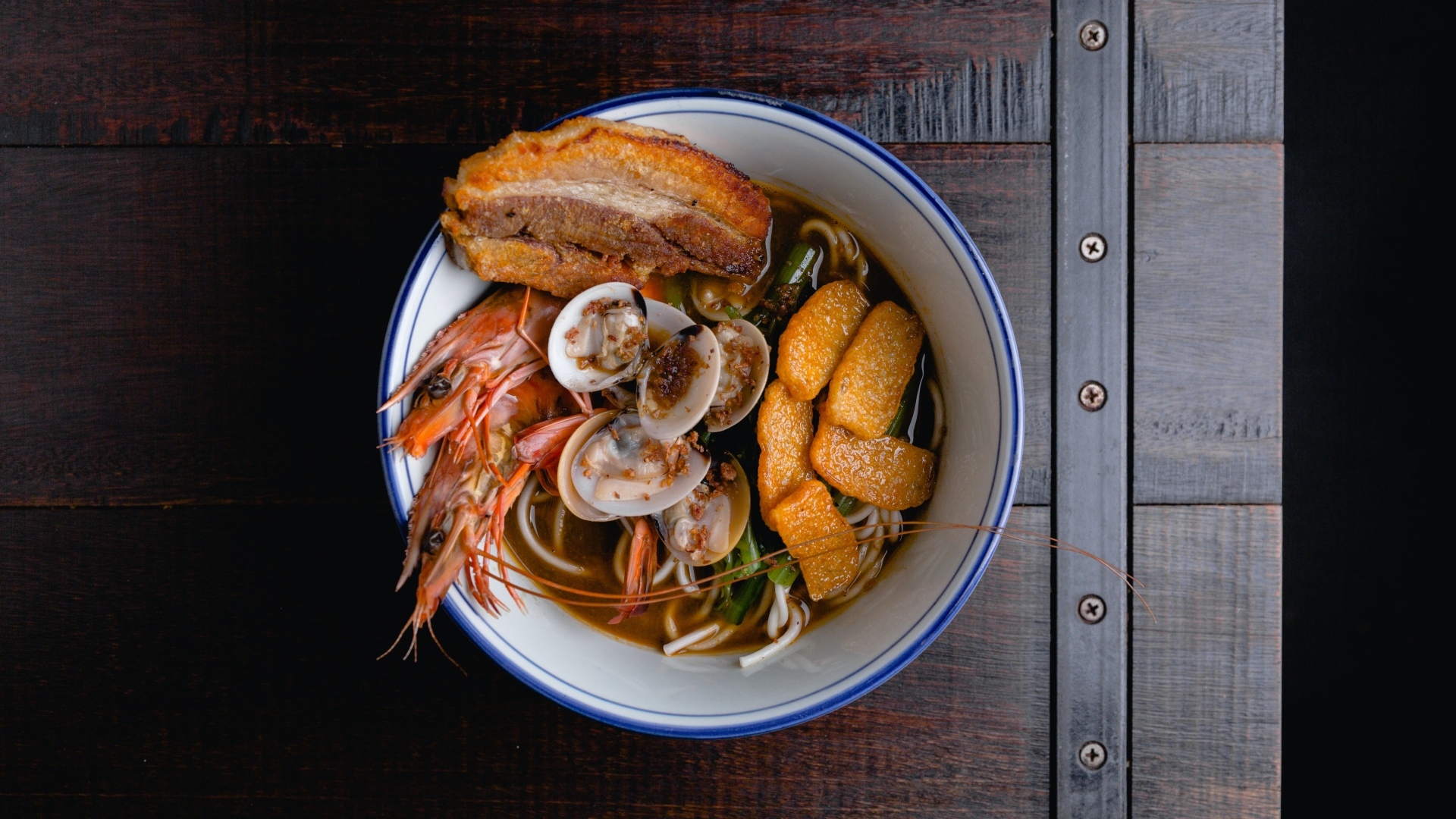 Суп с лапшой и морепродуктами на деревянном столе