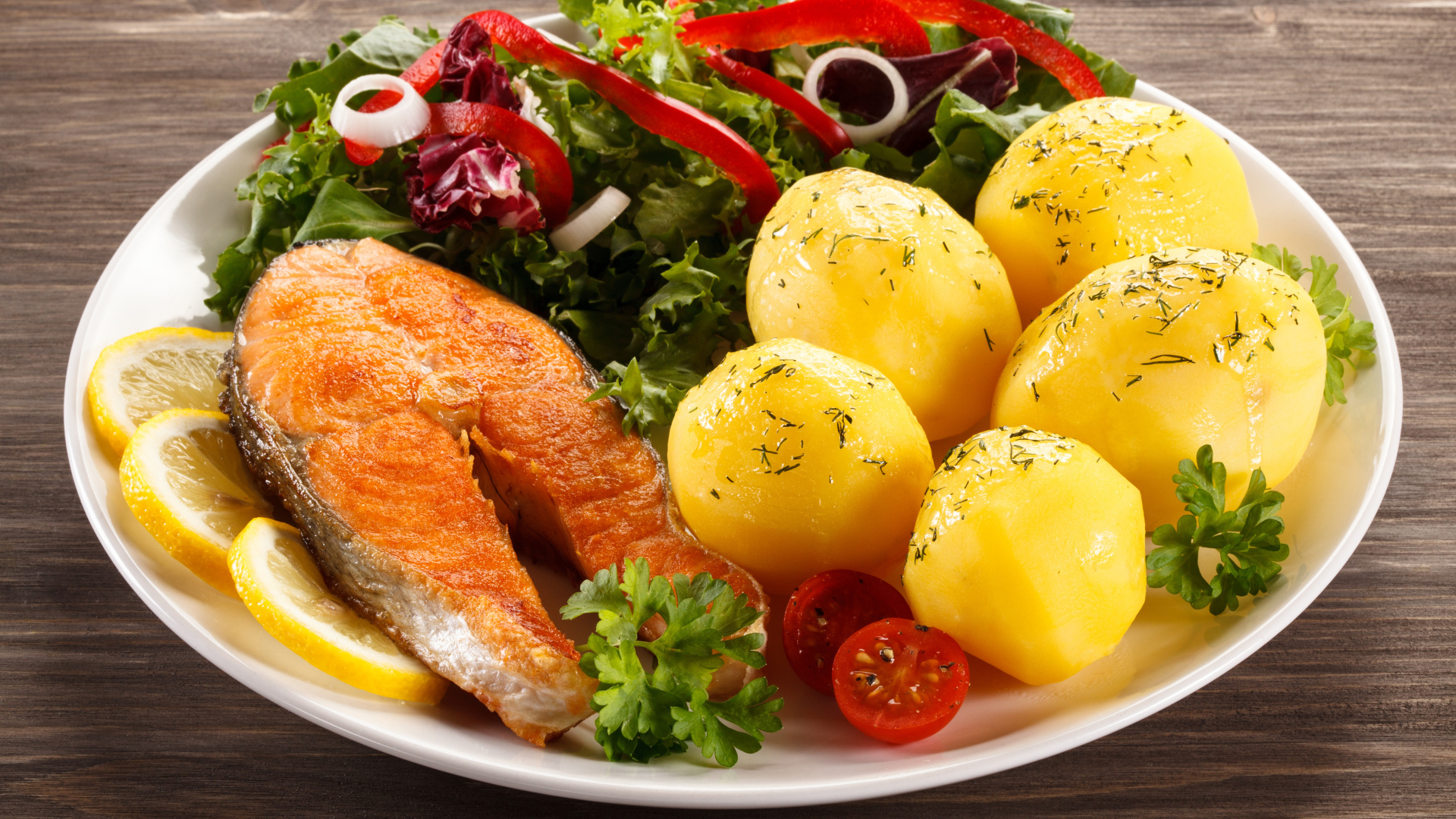 Картофель с кусочками рыбы и зеленью на тарелке