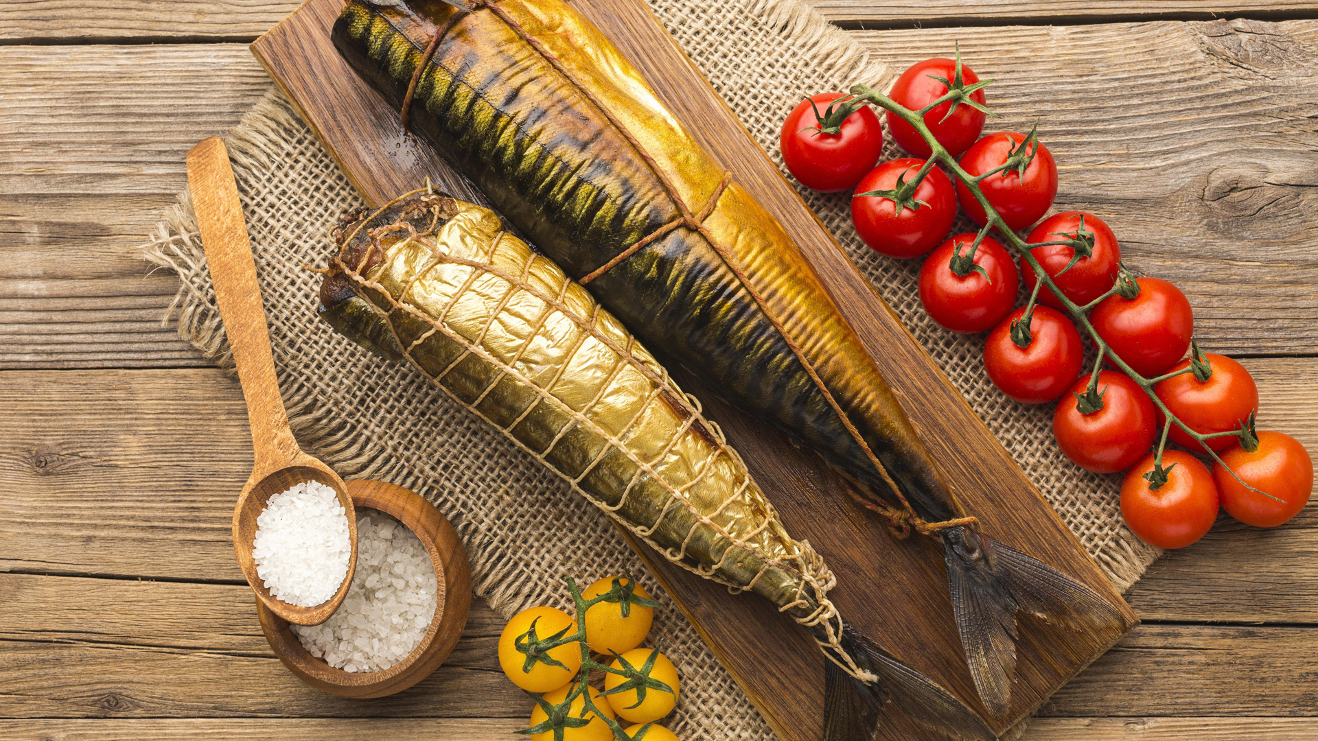 Две копченые скумбрии на столе с помидорами