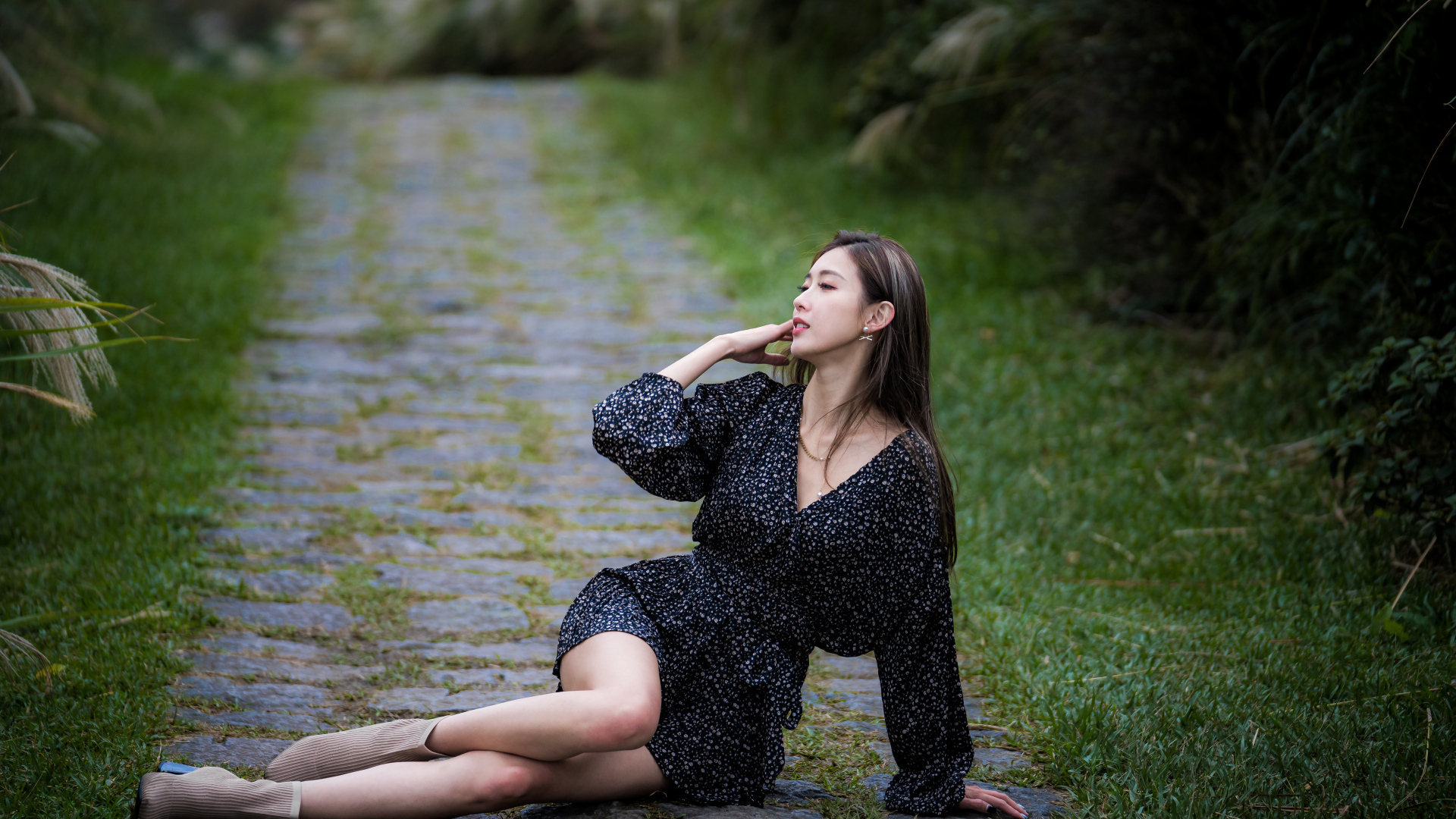 Девушка азиатка в платье лежит на дороге в парке