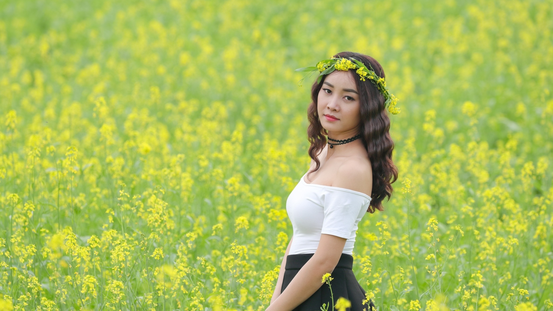 Девушка азиатка стоит на рапсовом поле