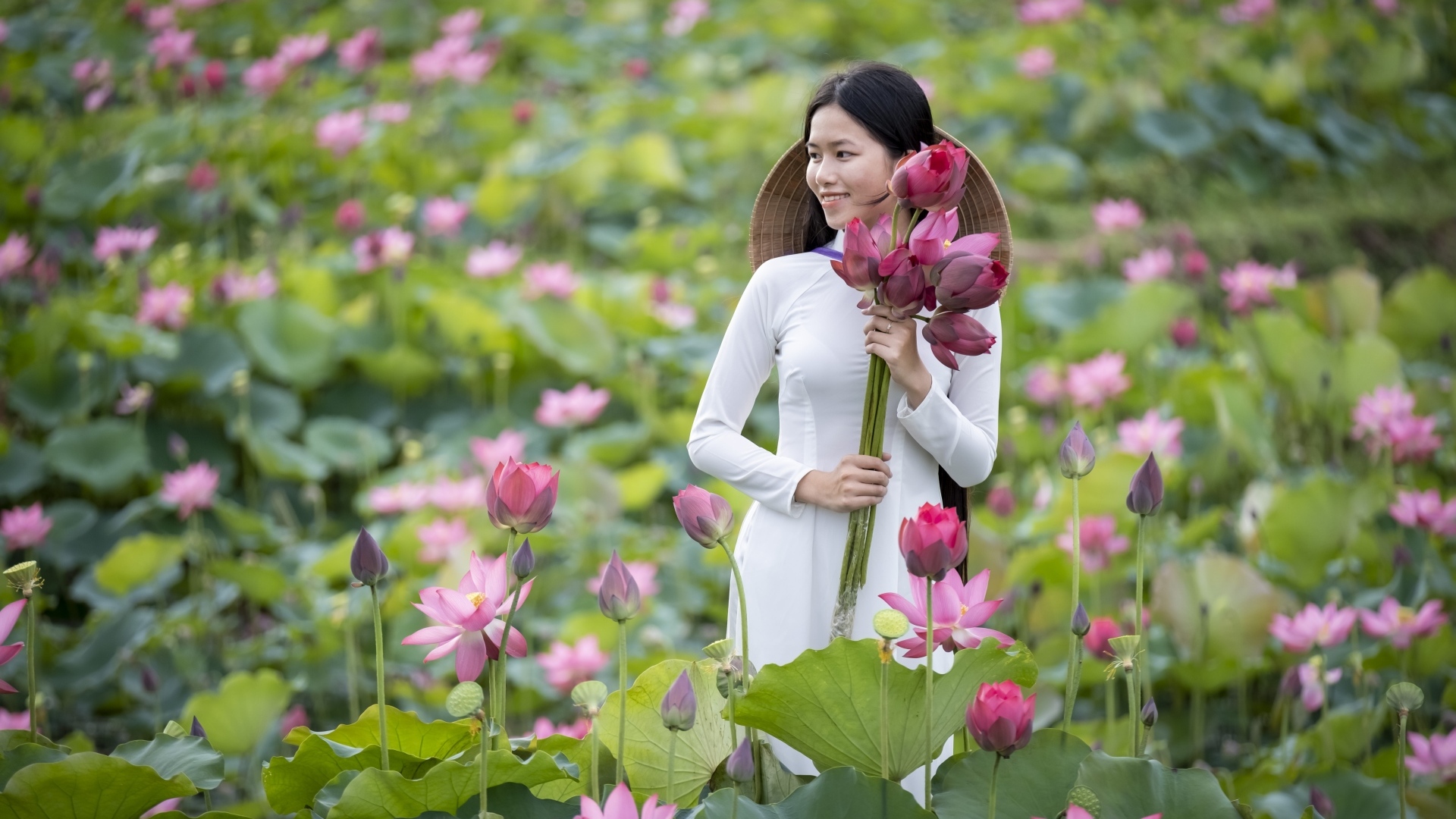 Девушка азиатка с розовыми цветами лотоса в руках