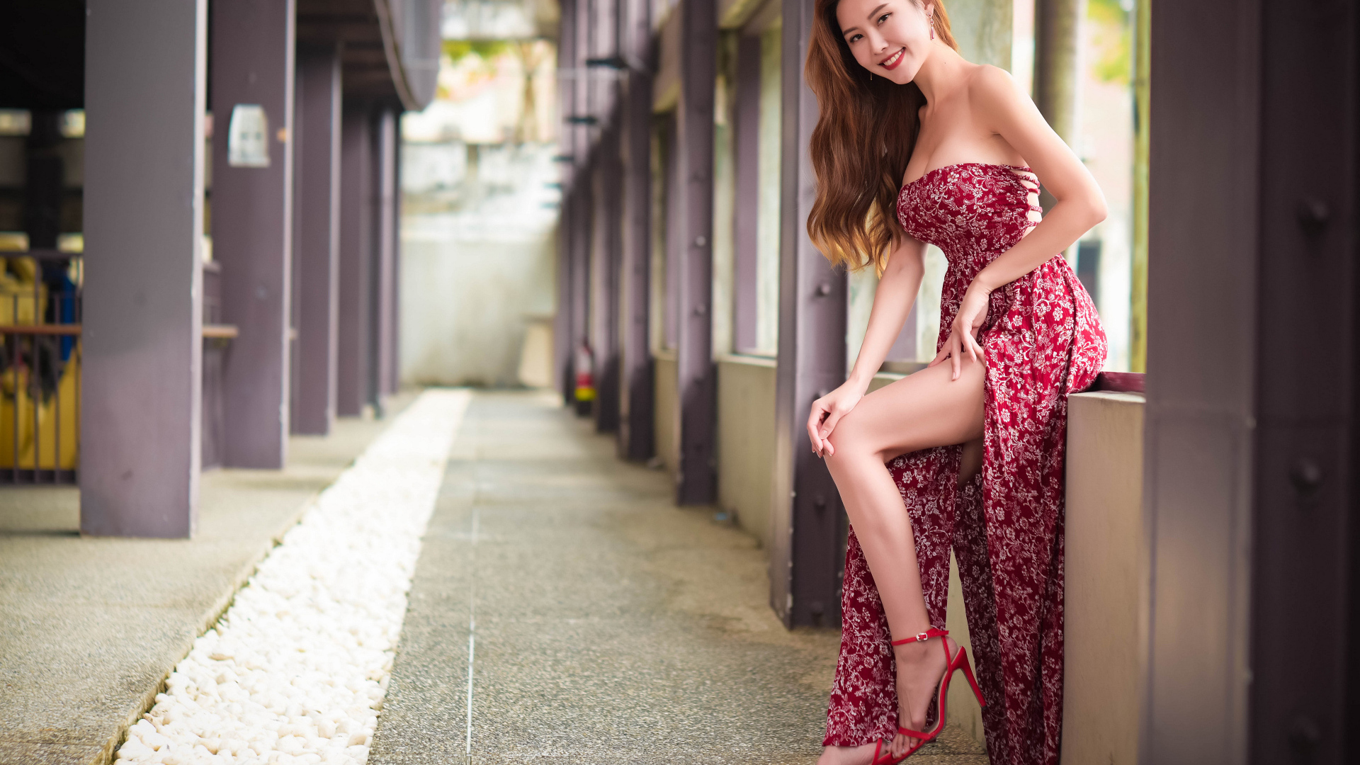 Азиатка в платье стоит у окна