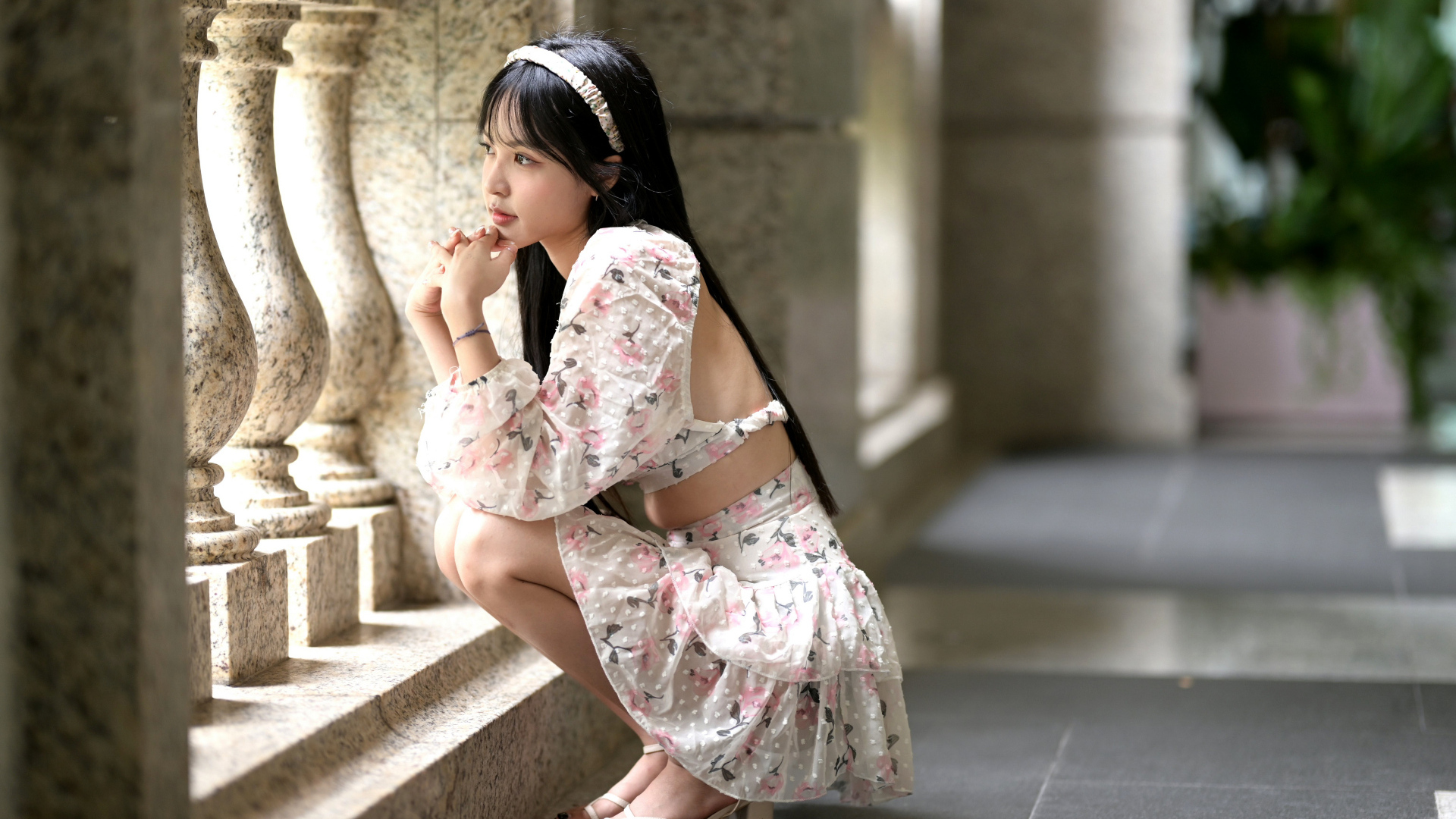 Красивая девушка азиатка в костюме сидит у стены