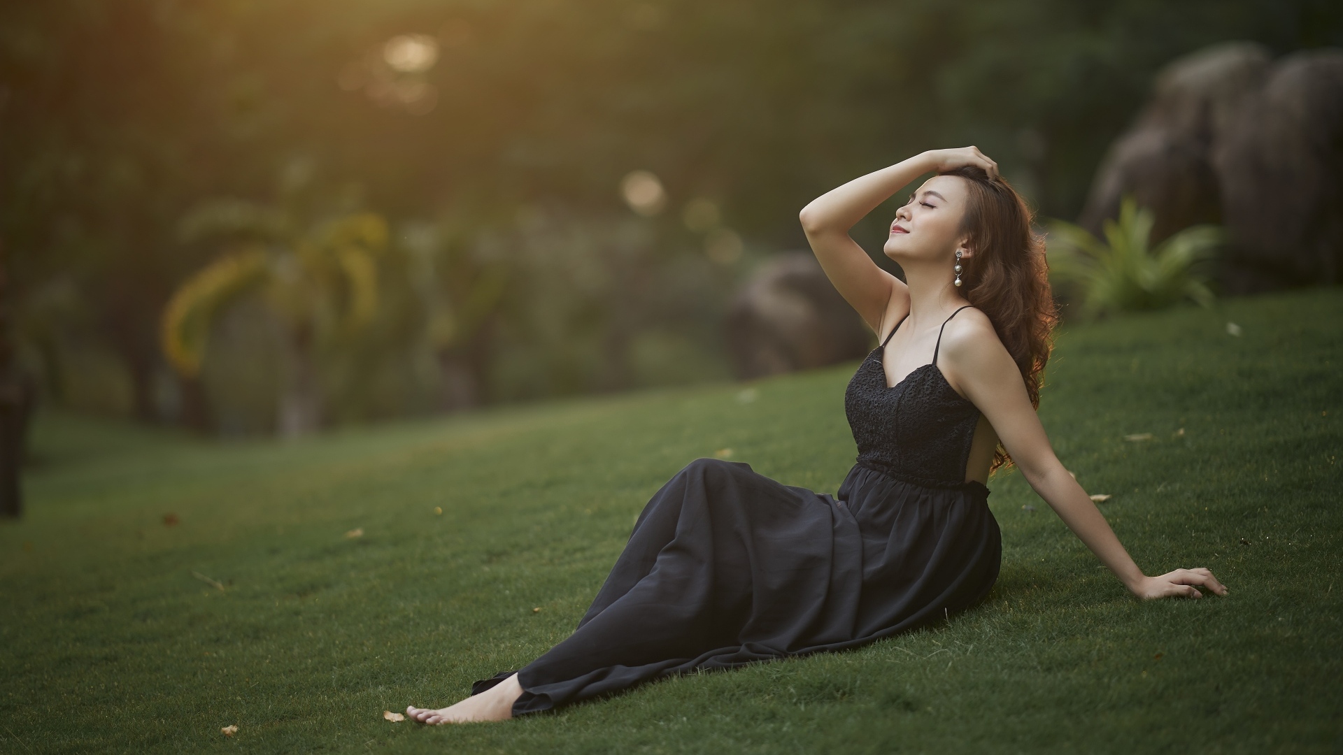 Красивая азиатка с закрытыми глазами в черном платье