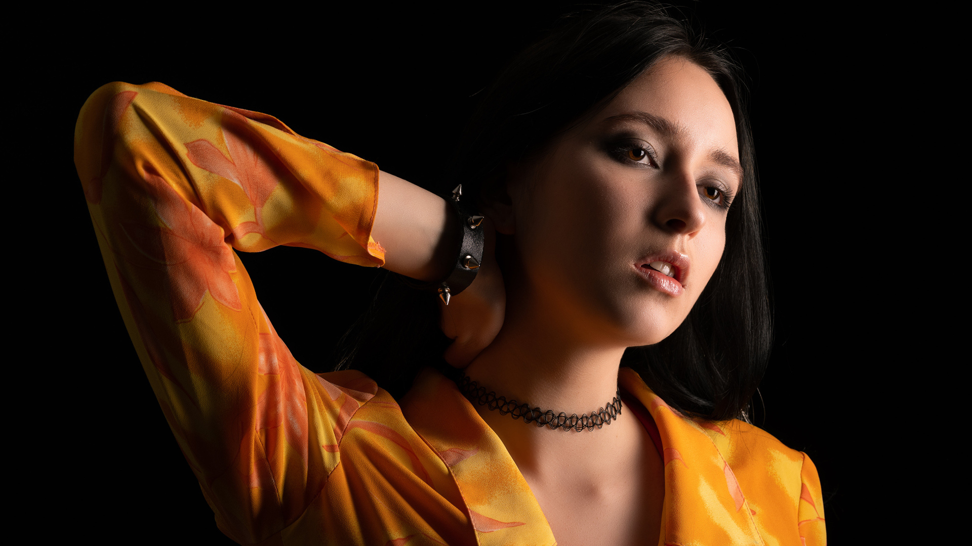 Красивая девушка шатенка с рукой в волосах на черном фоне