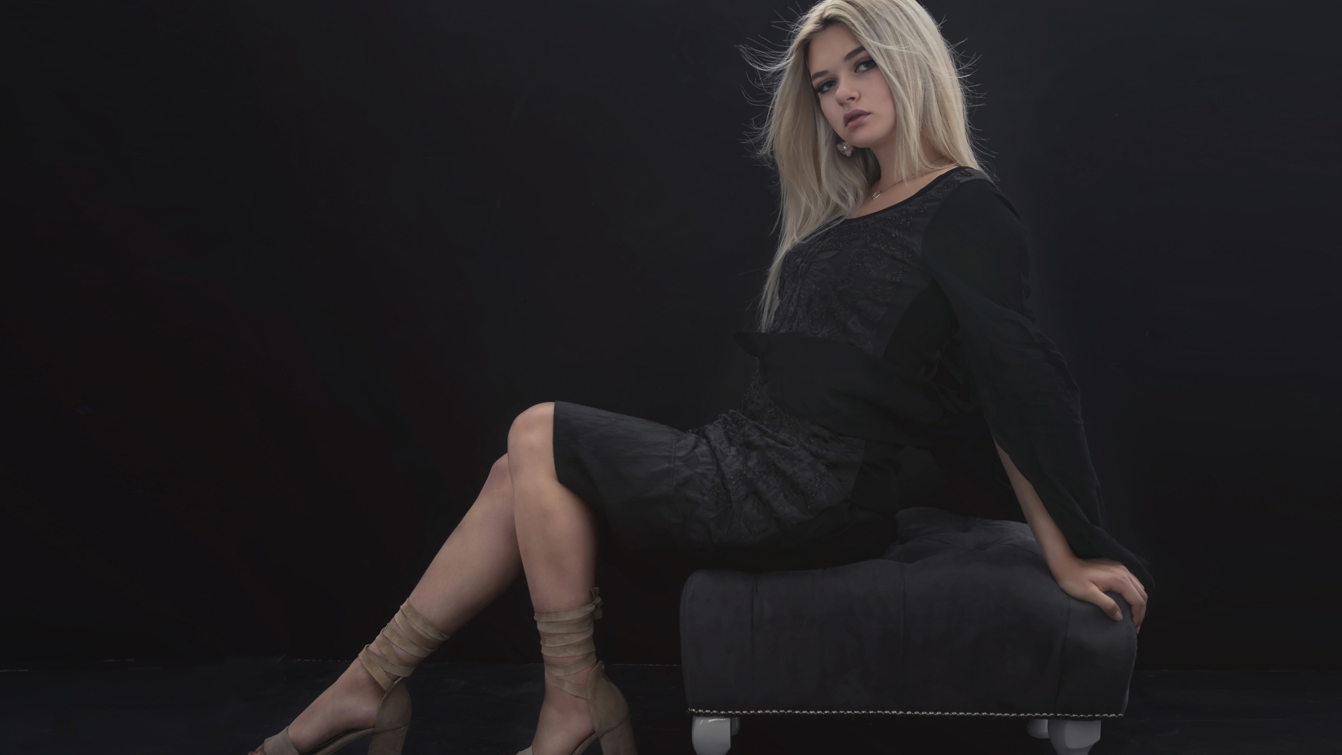 Красивая девушка в черном платье сидит на кресле