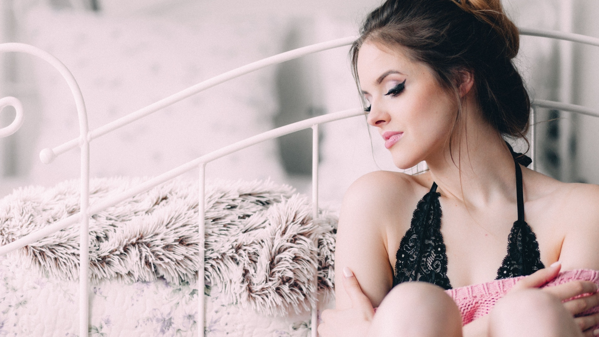 Красивая девушка сидит на полу у кровати 