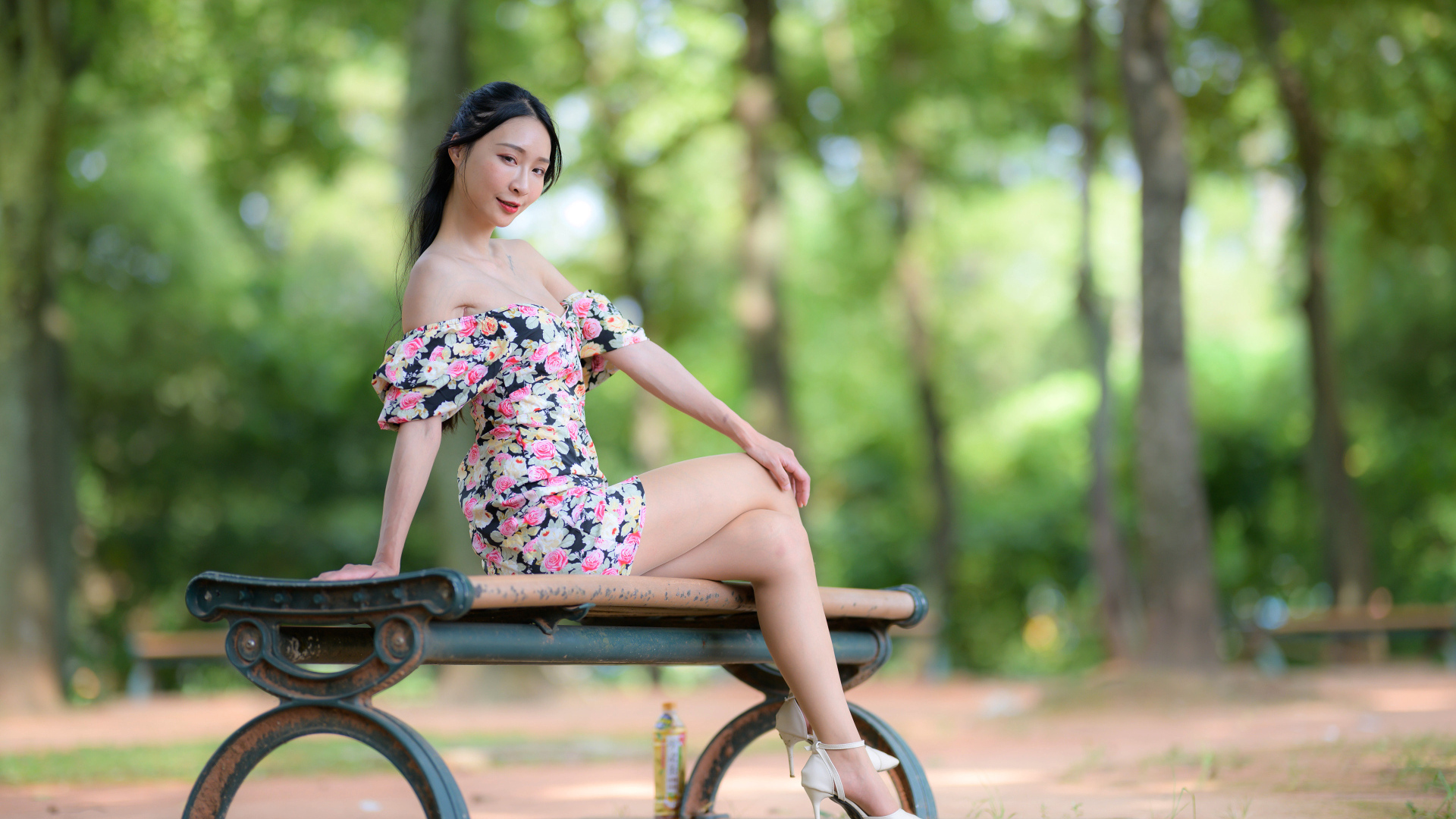 Милая девушка азиатка в платье сидит на лавке в парке