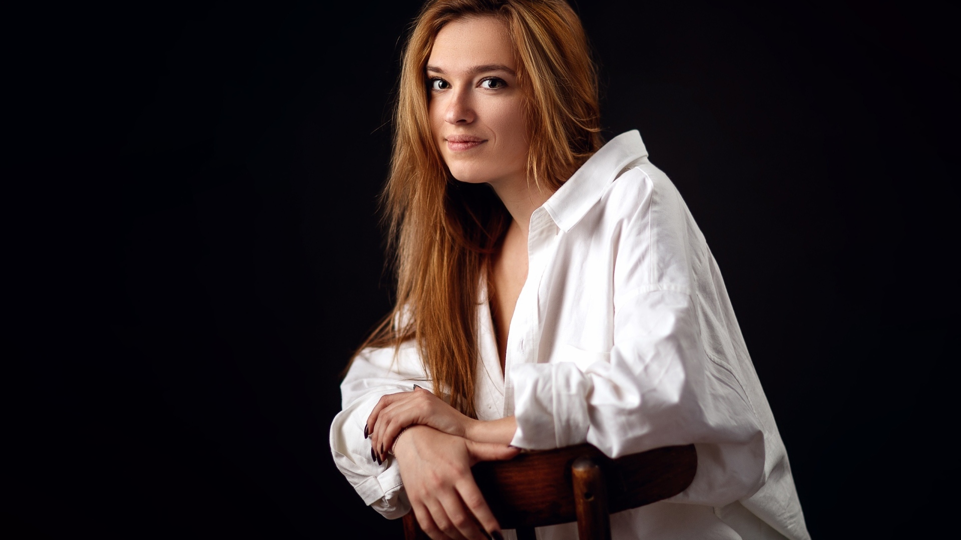 Милая девушка в белой рубашке сидит на стуле