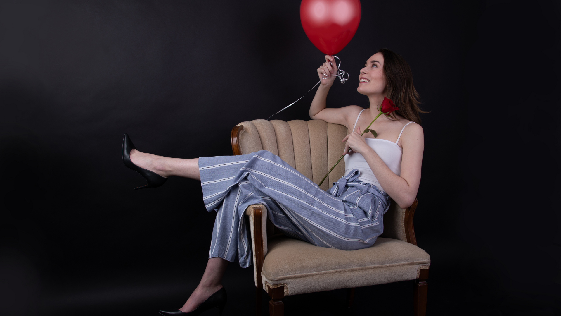 Девушка с шариком и розой сидит в кресле