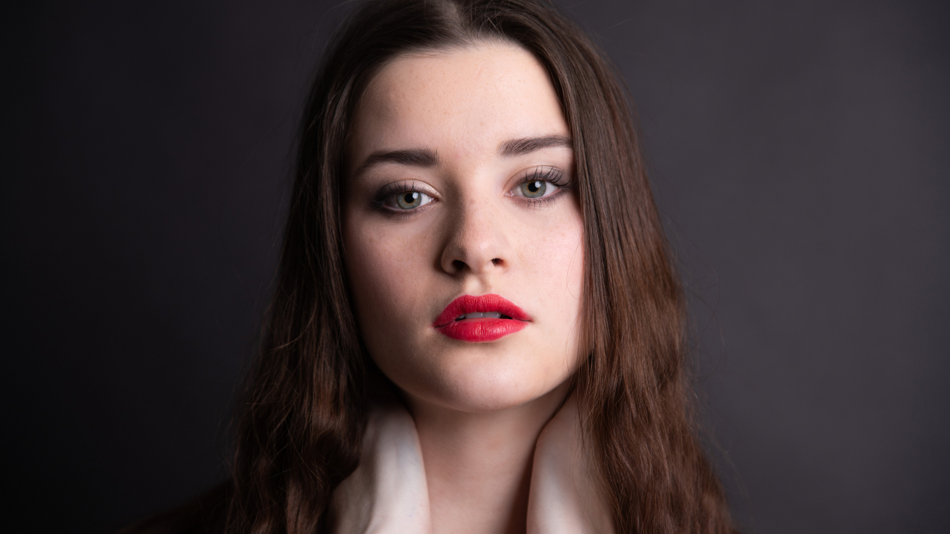 Девушка с красными губами на сером фоне