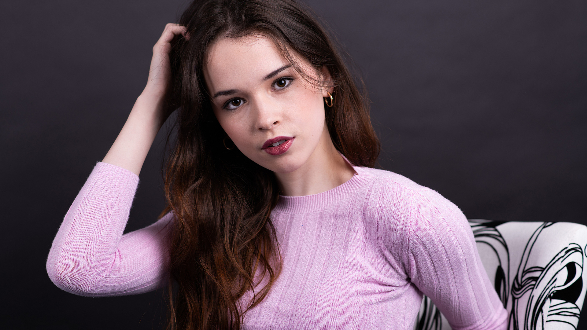 Длинноволосая шатенка в свитере с рукой в волосах