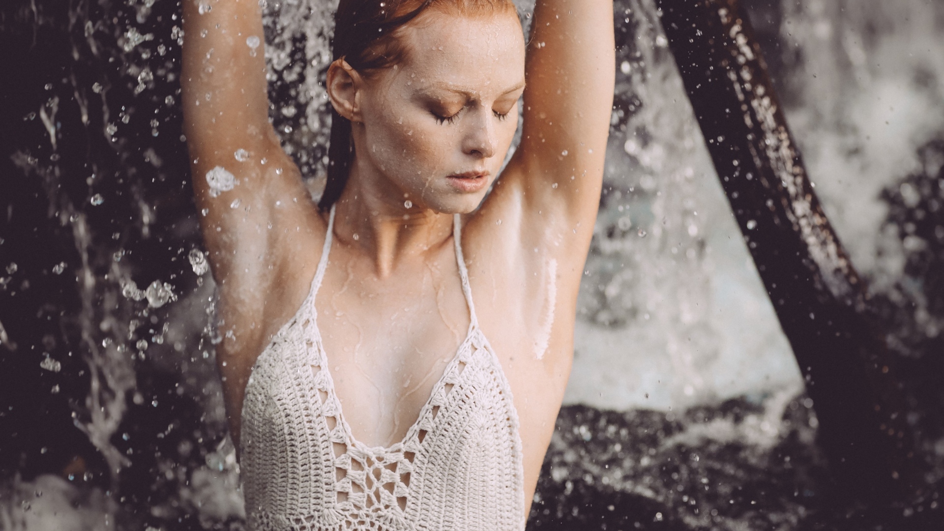 Рыжеволосая девушка в брызгах воды