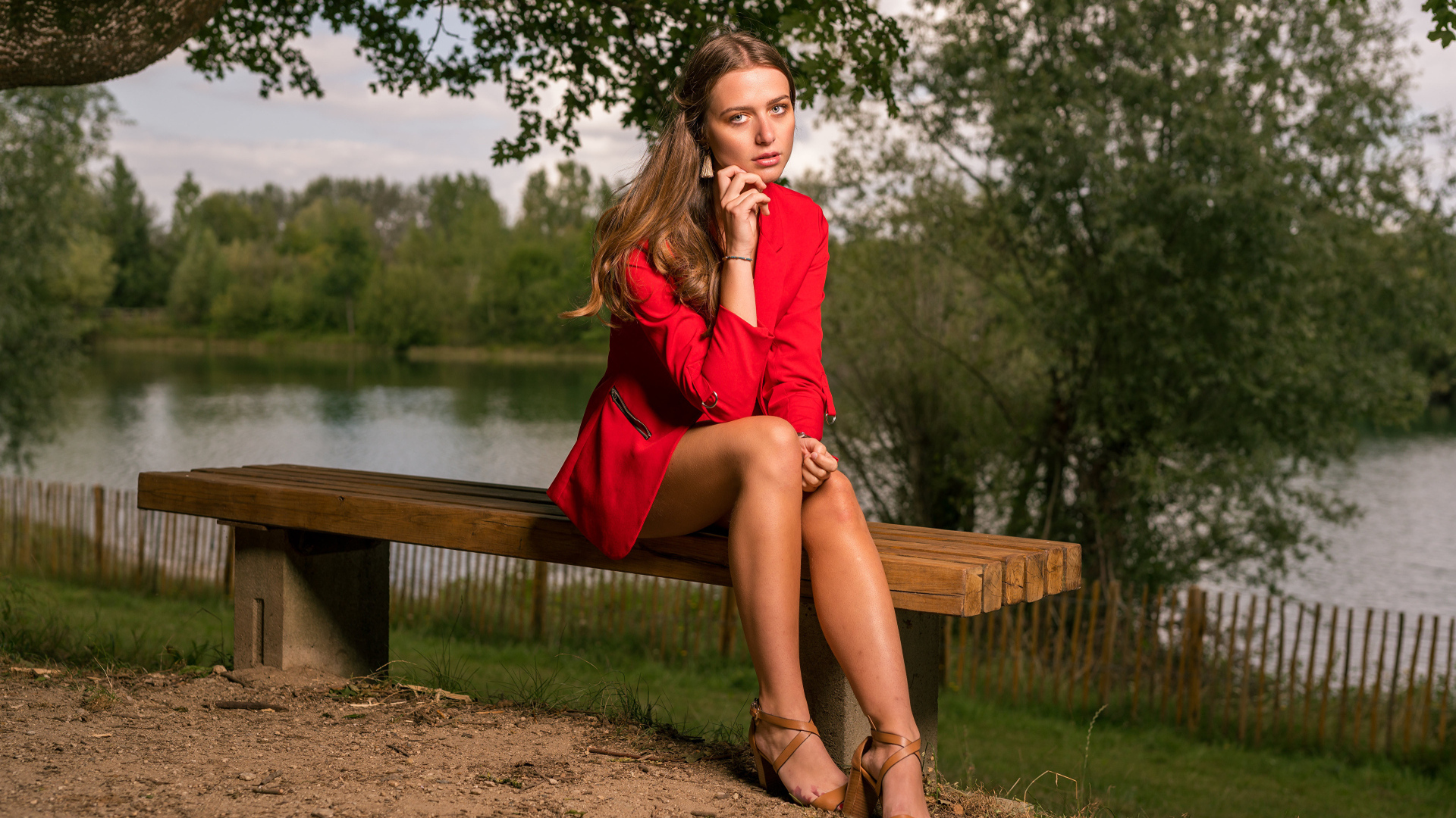 Грустная девушка в красном пальто сидит на лавке