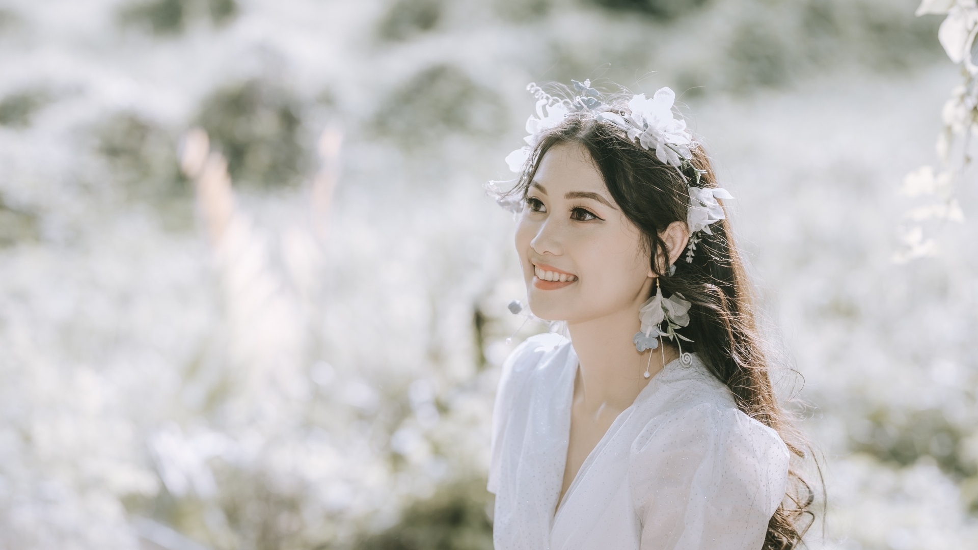 Улыбающаяся девушка азиатка в белом платье на поле